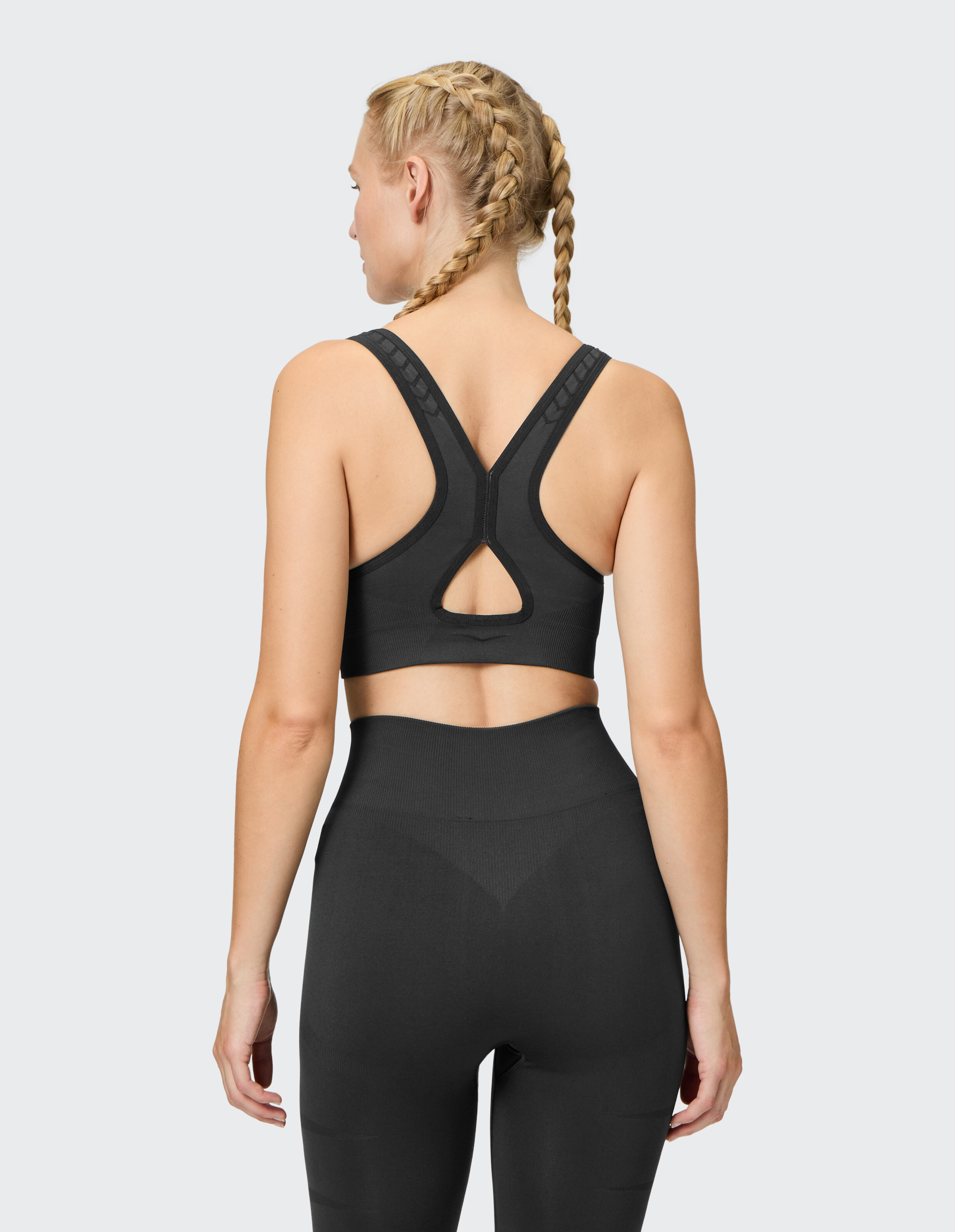 Rückansicht einer Frau in einem schwarzen Sport-BH und passenden Leggings.
