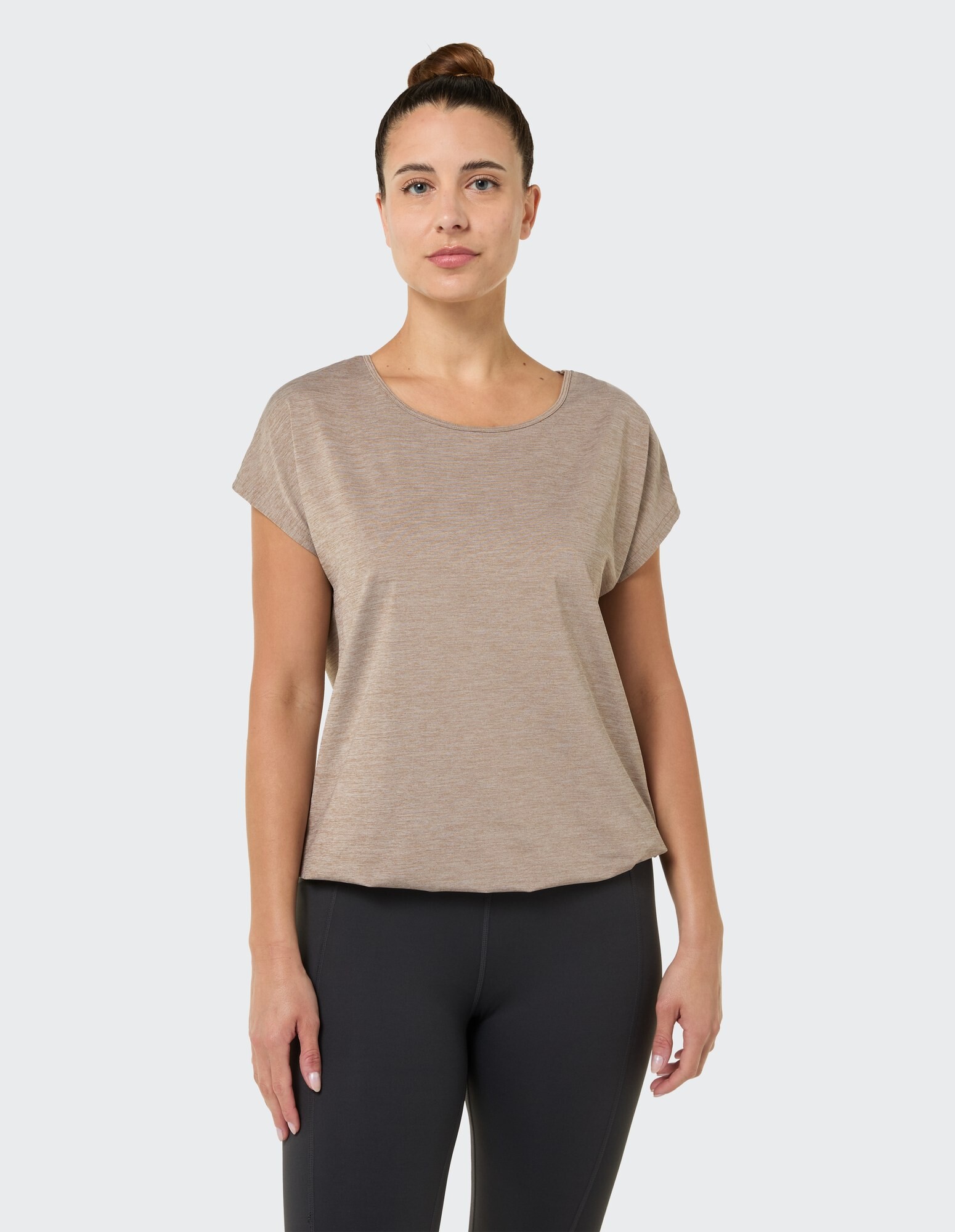 Lässiges beiges Kurzarm-Top gepaart mit schwarzen Leggings, perfekt zum Entspannen.