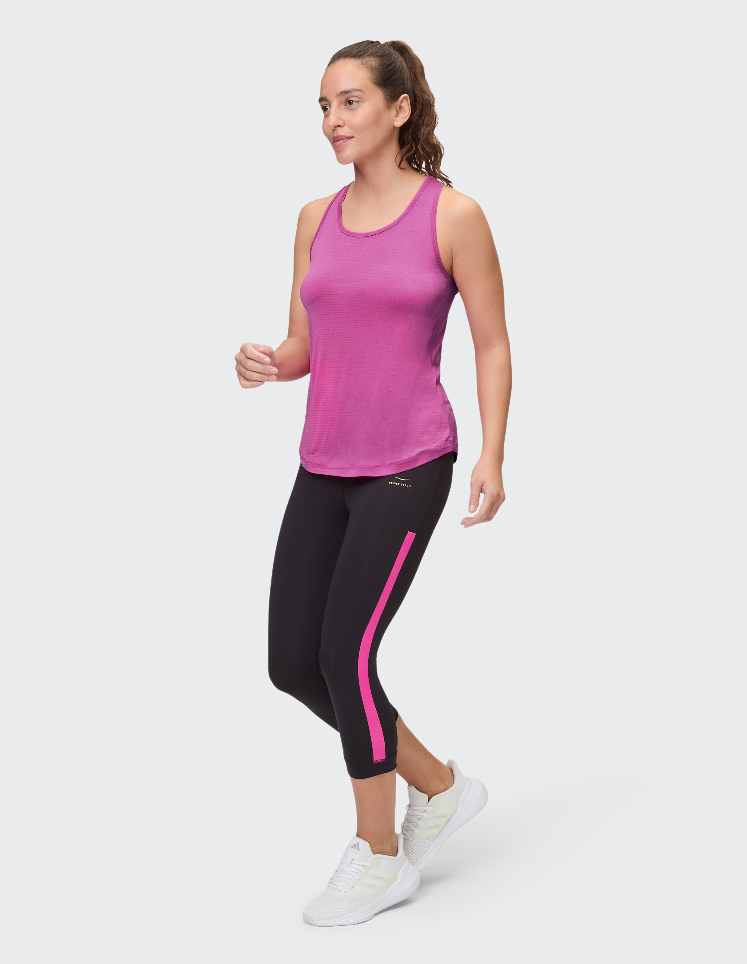 Frau trägt ein rosa Tanktop und schwarze, kurze Leggings für lässige Aktivkleidung.