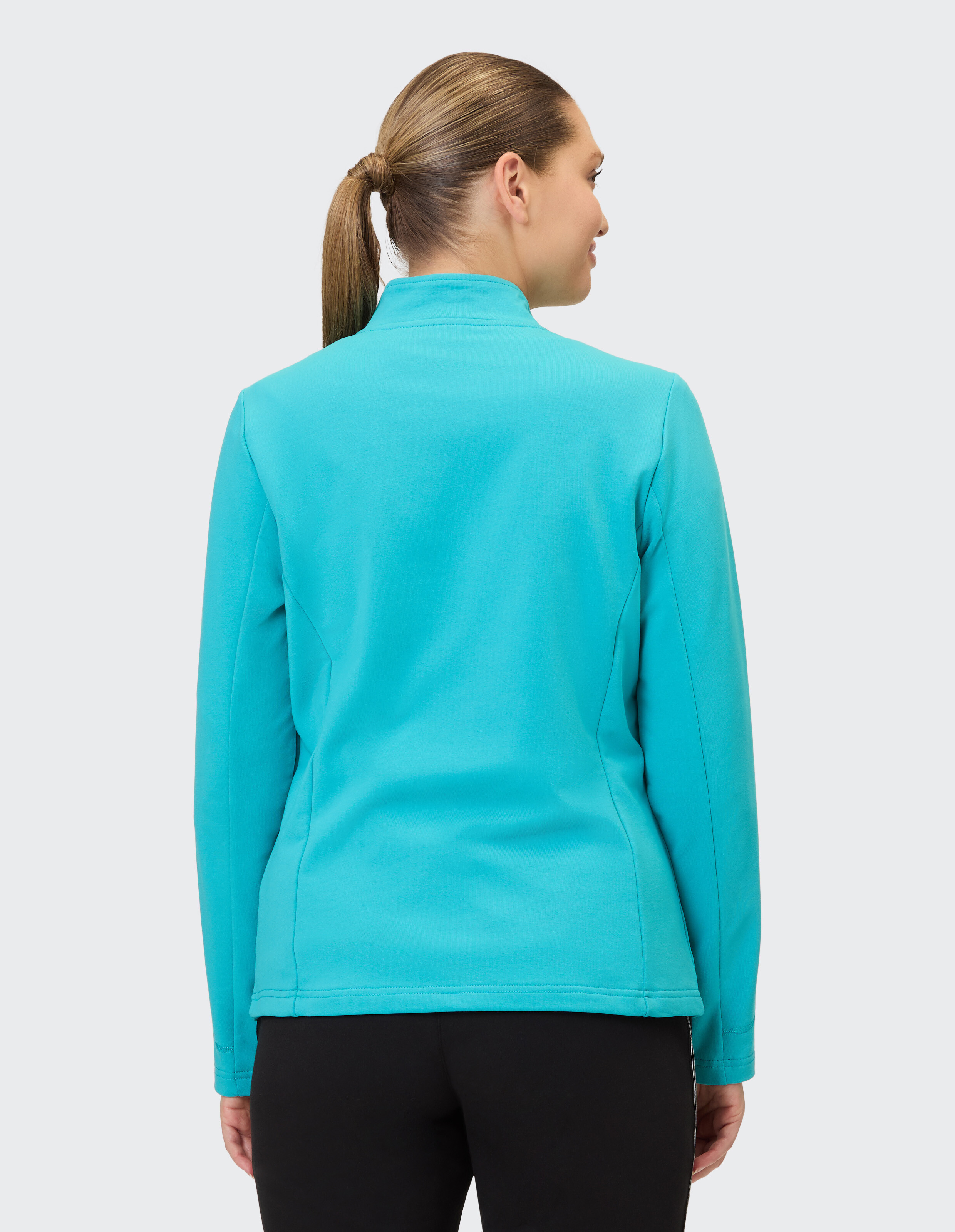 Rückansicht einer Frau in einer türkisfarbenen Freizeitjacke, perfekt zum Entspannen.