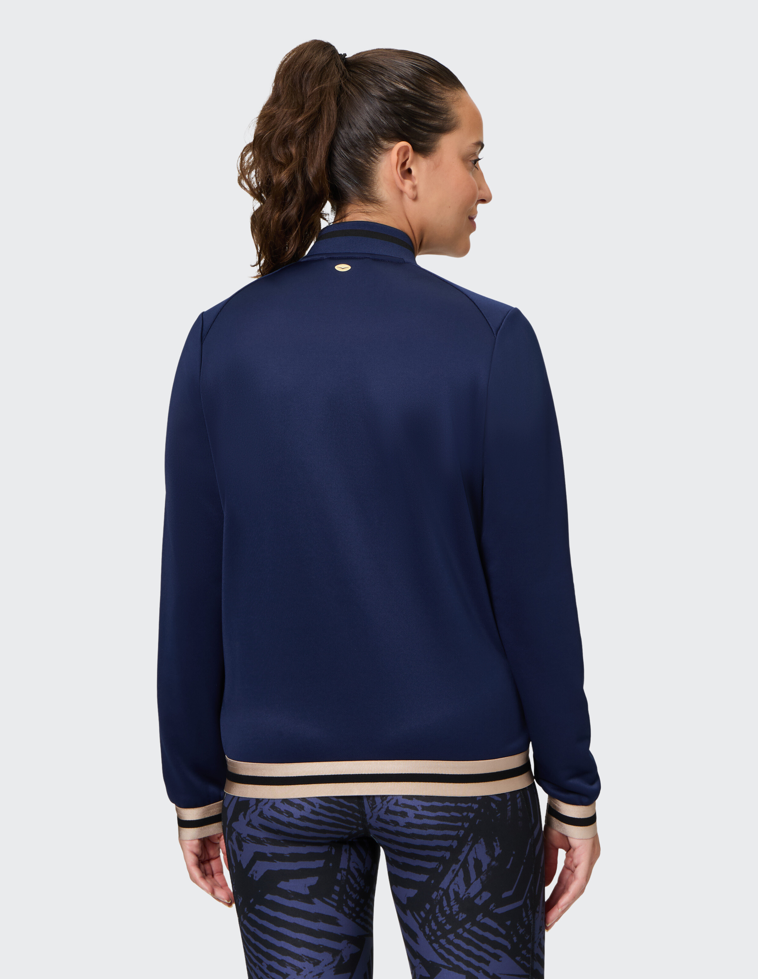 Frau trägt eine marineblaue, lässige Jacke mit Reißverschluss und gestreiftem Saum und Bündchen.