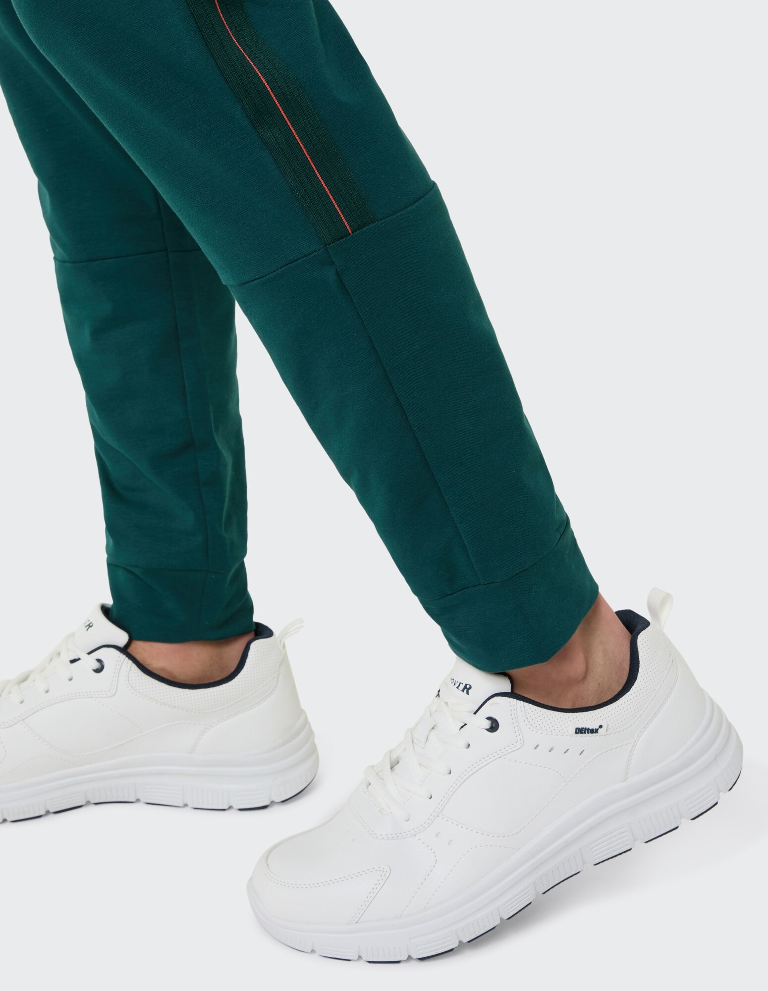 Nahaufnahme einer grünen Jogginghose gepaart mit weißen Turnschuhen, ideal für Freizeitkleidung.