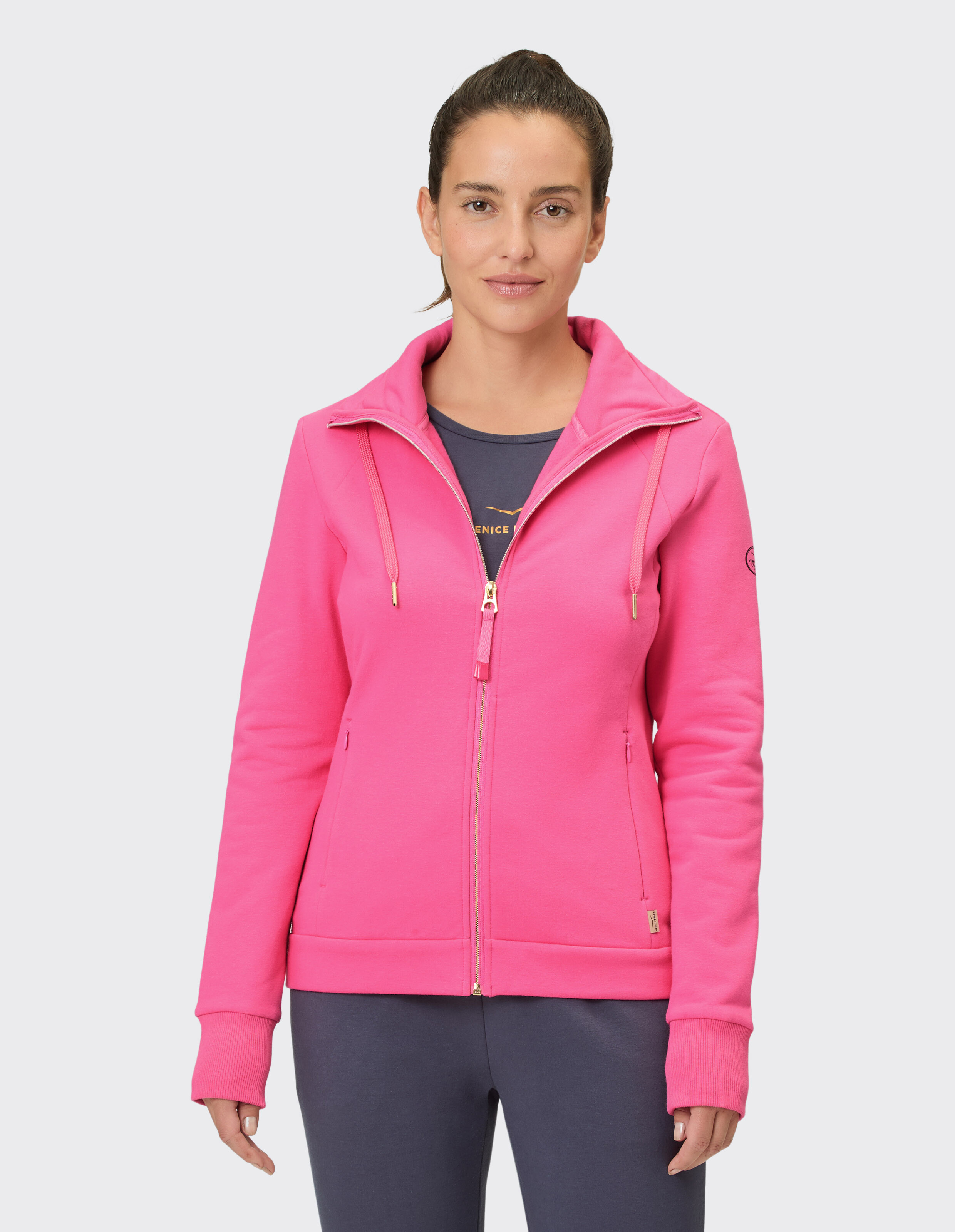Frau trägt einen rosa Kapuzenpullover mit Reißverschluss, perfekt für Freizeitausflüge und zum Faulenzen.