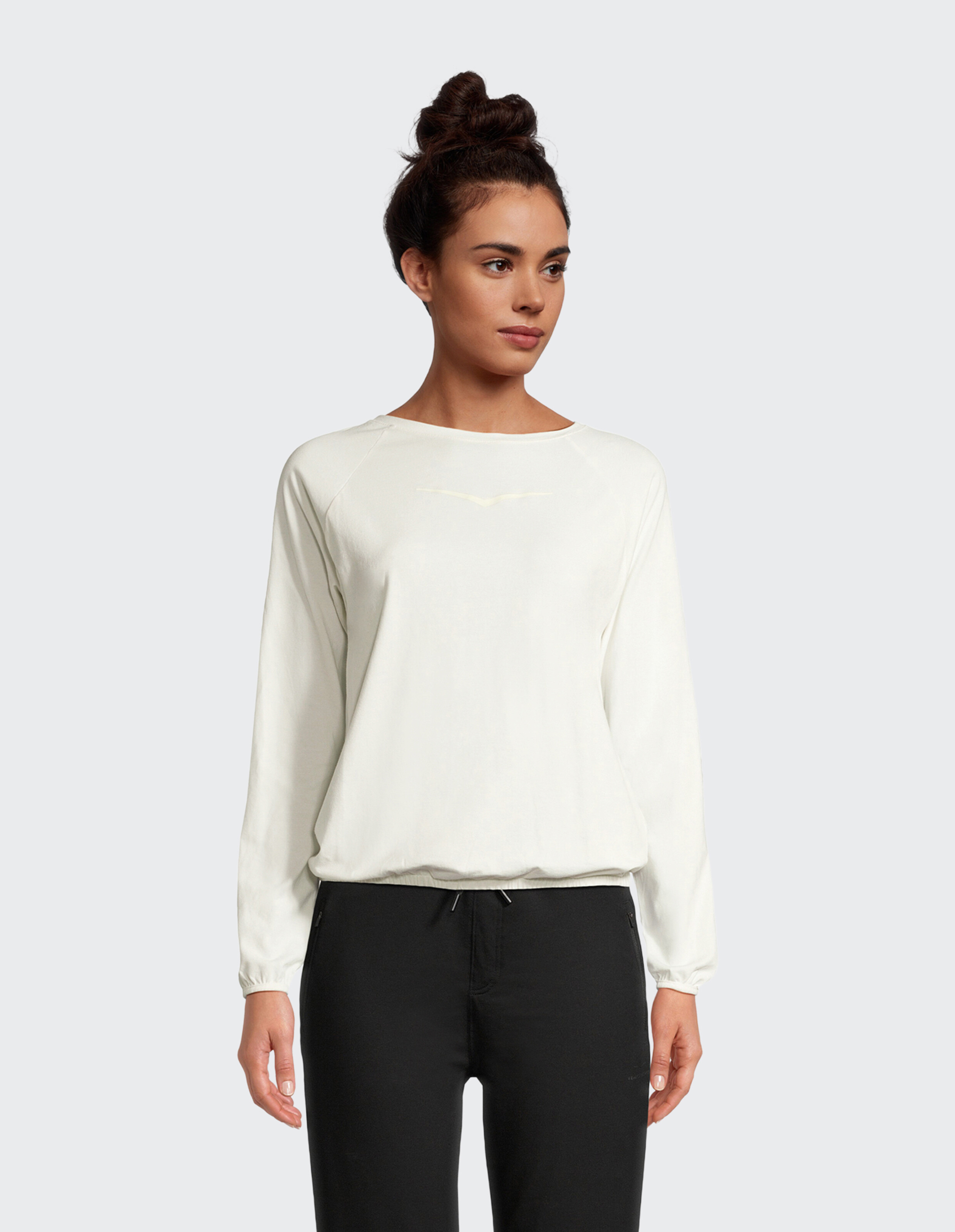 Frau trägt ein weißes, langärmliges Freizeit-Sweatshirt mit gerafftem Saum.