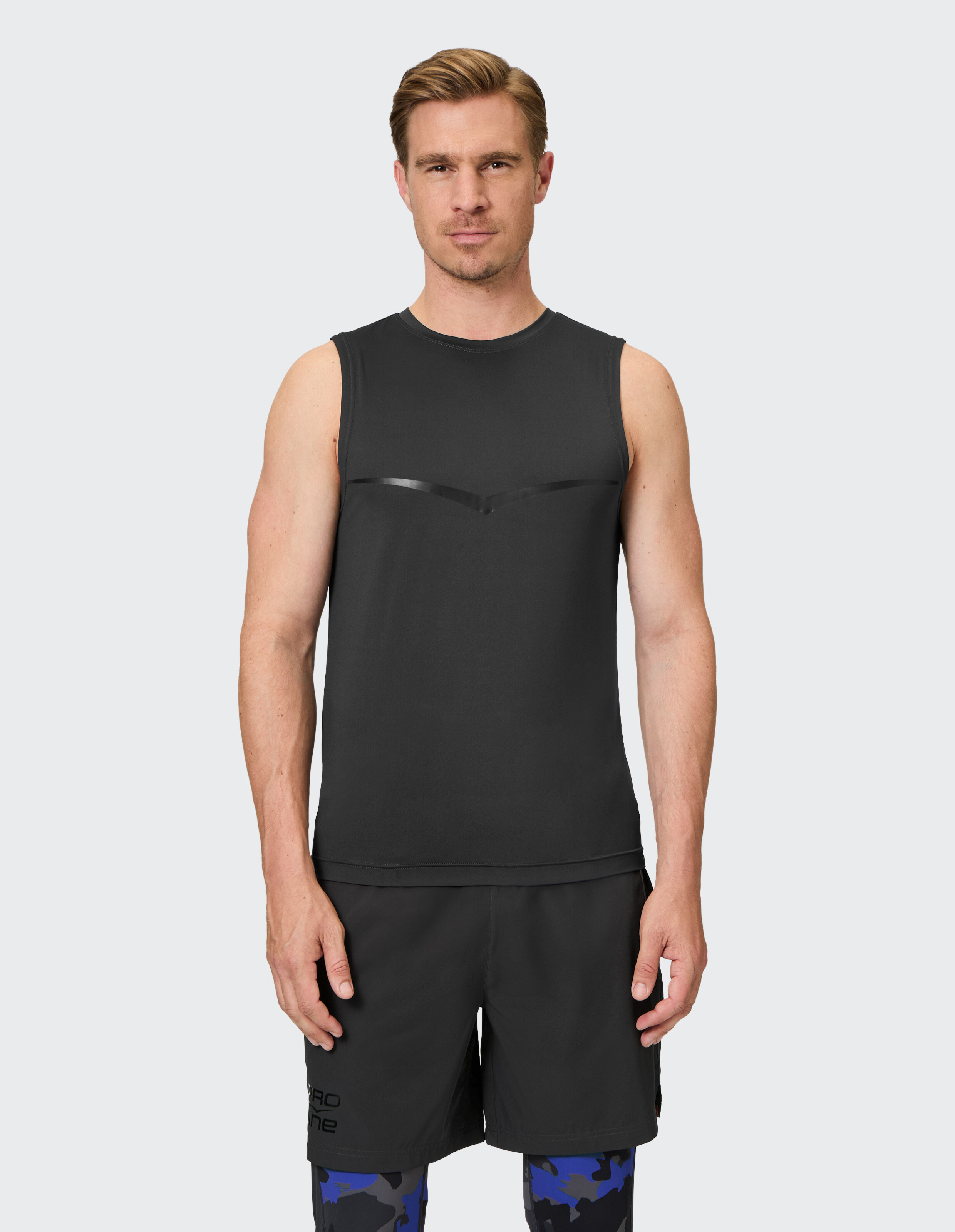 Mann trägt ein schwarzes, ärmelloses Sportshirt und passende Shorts für einen lässigen Trainingsstil.