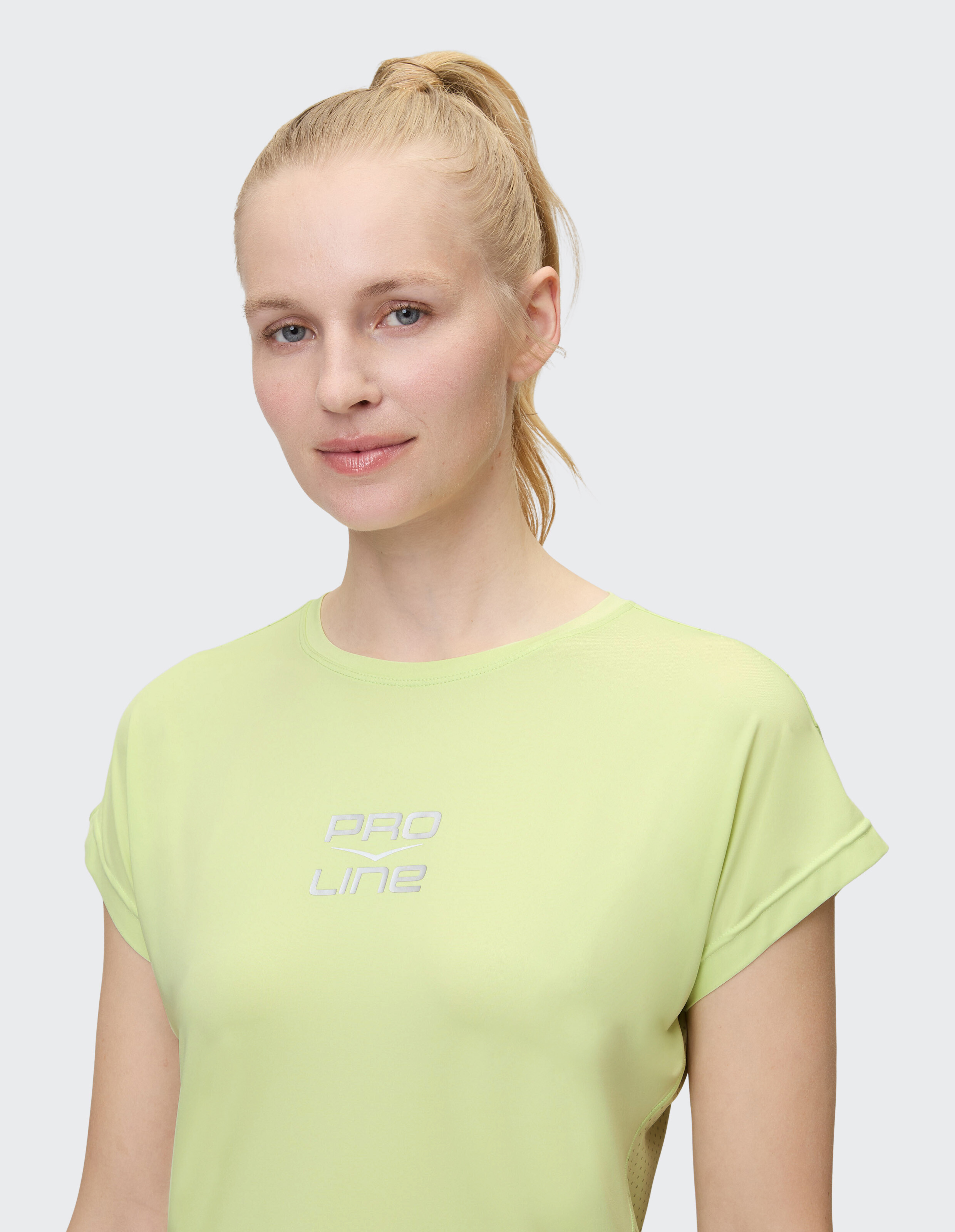 Frau trägt ein hellgrünes PRO LINE-T-Shirt mit aufgerollten Ärmeln.