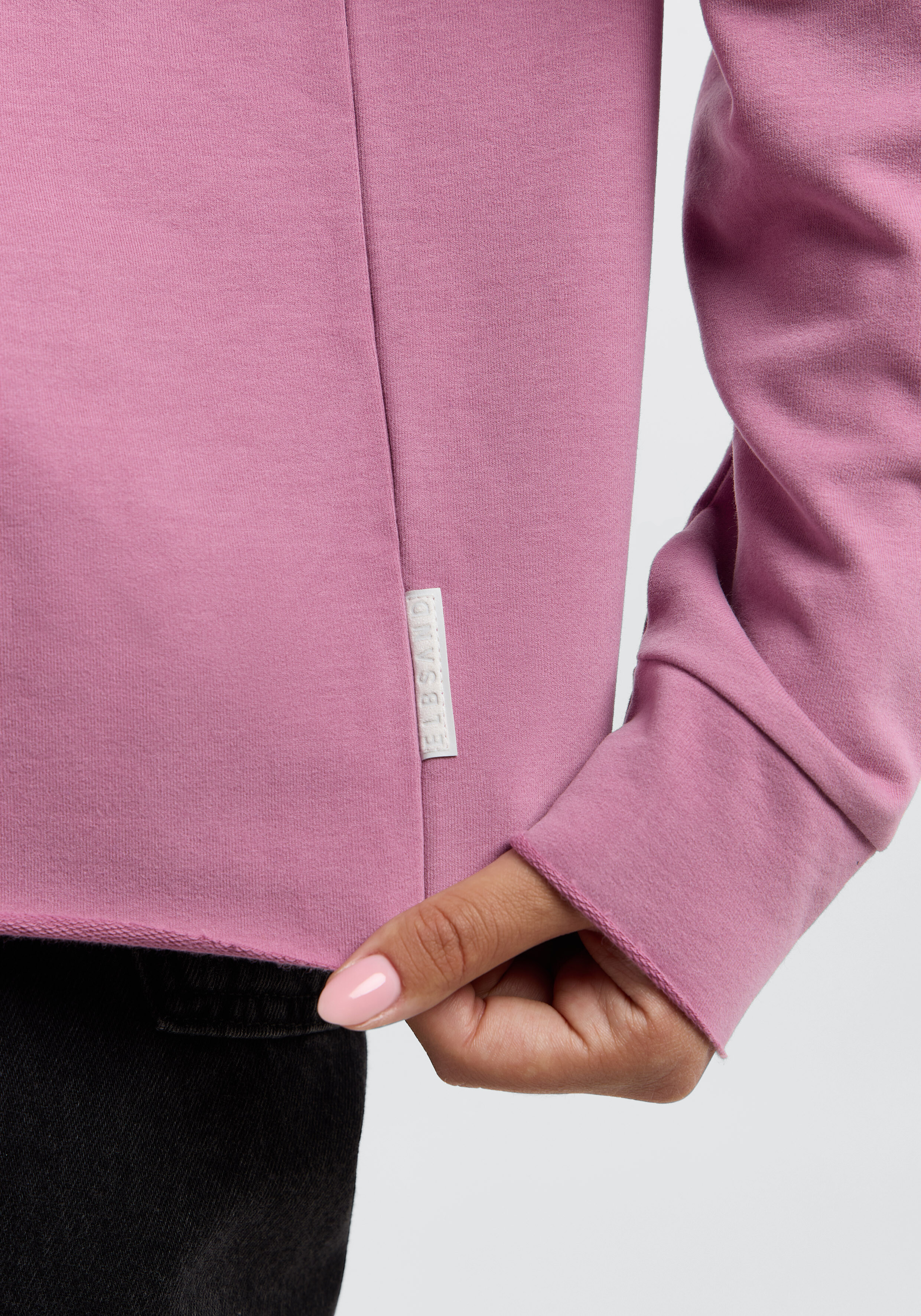 Nahaufnahme eines altrosa ELBSAND-Sweatshirts mit offenem Saum und seitlichem Markenetikett.