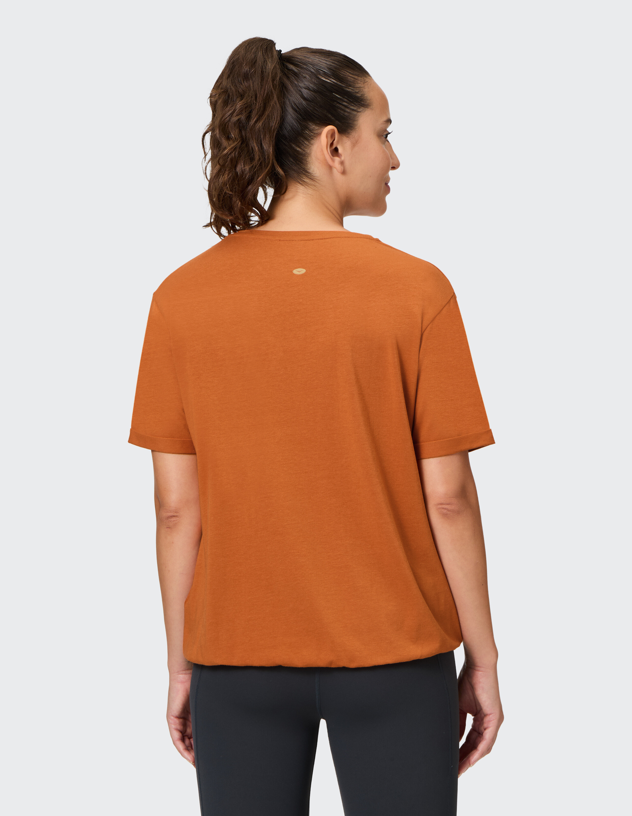 Rückansicht einer Frau in einem orangefarbenen Freizeit-T-Shirt, perfekt zum Entspannen.