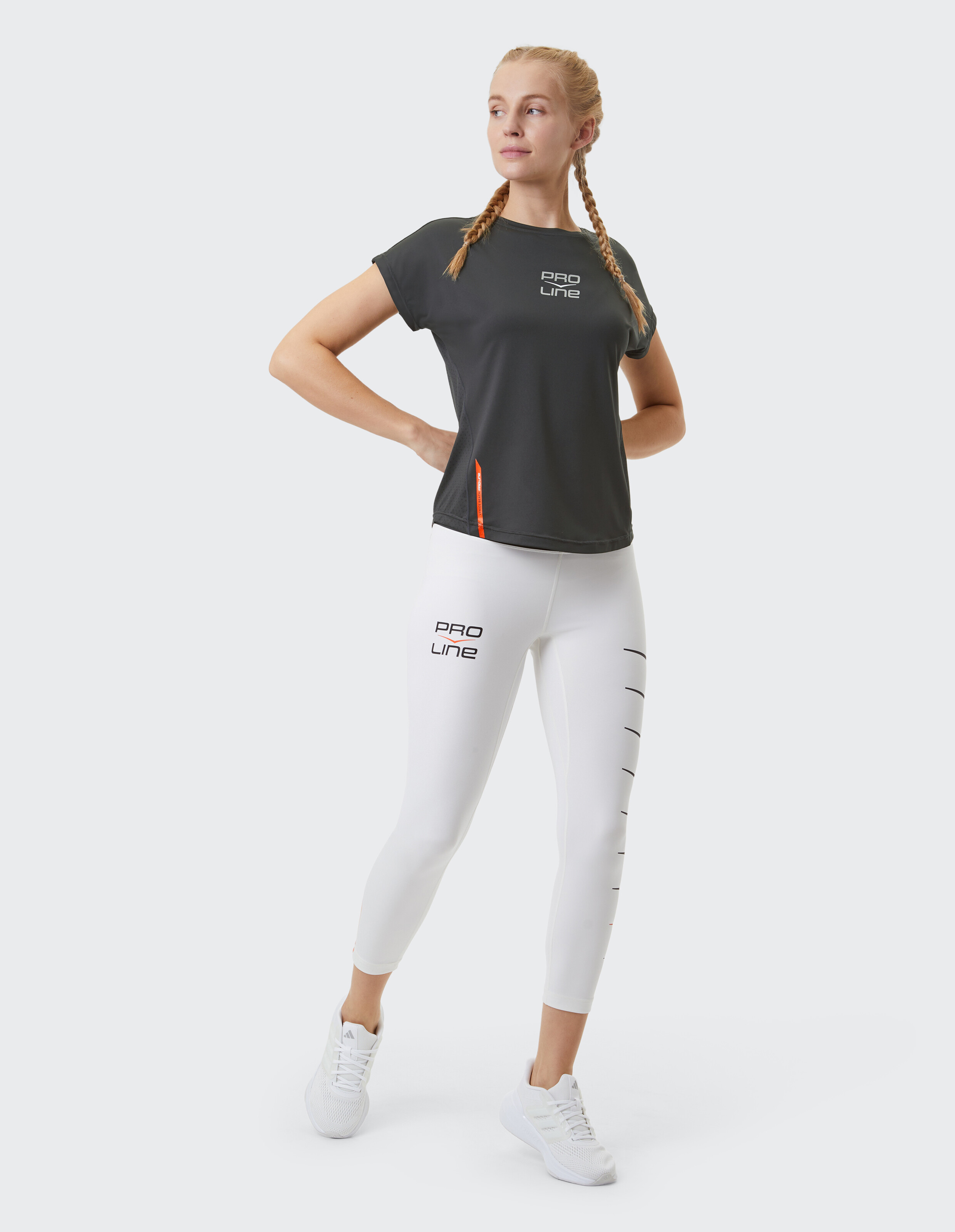 Frau trägt ein dunkelgraues Pro Line-T-Shirt und weiße Sportleggings.