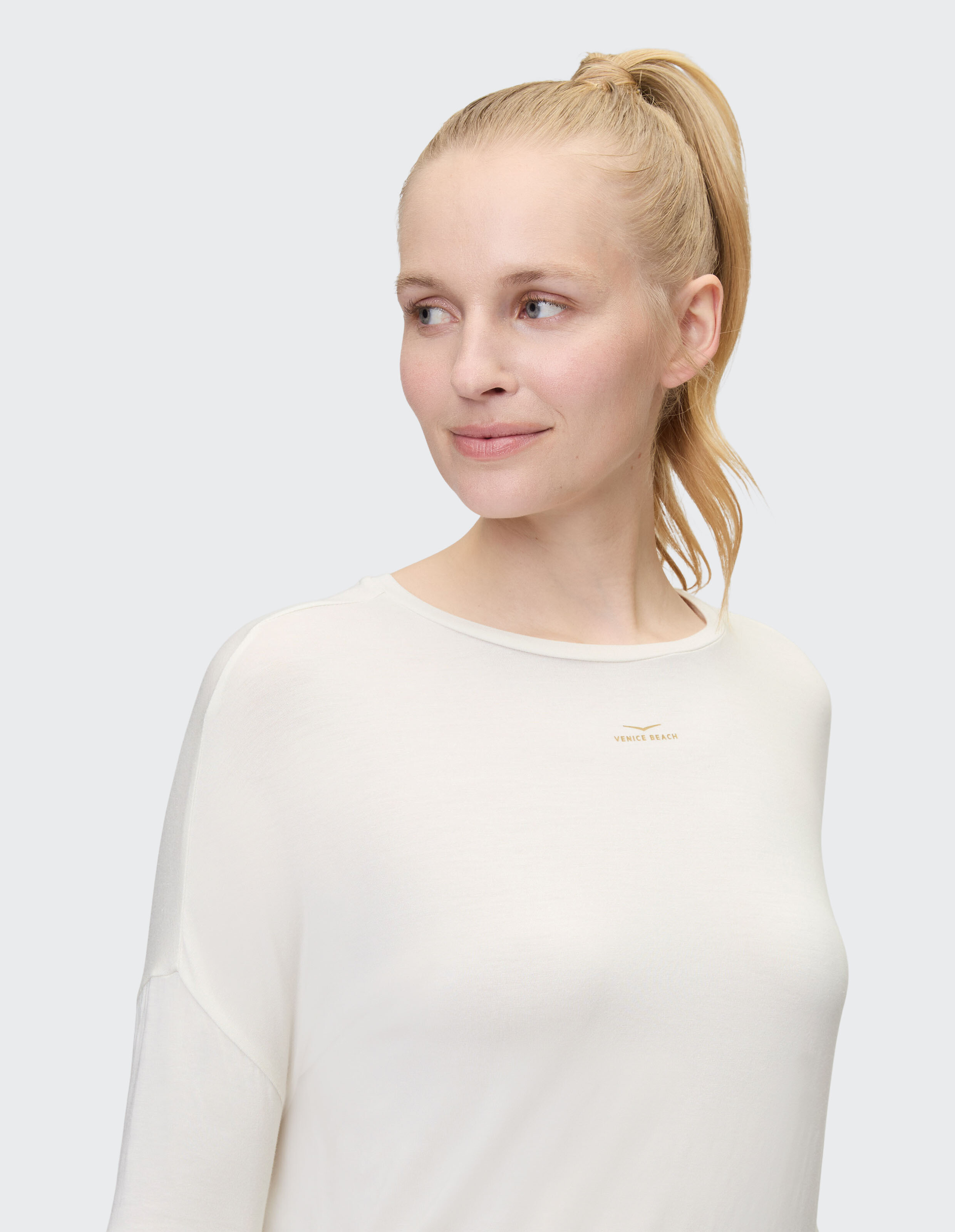 Nahaufnahme einer Frau in einem hellcremefarbenen Langarmshirt mit lockerer Passform.