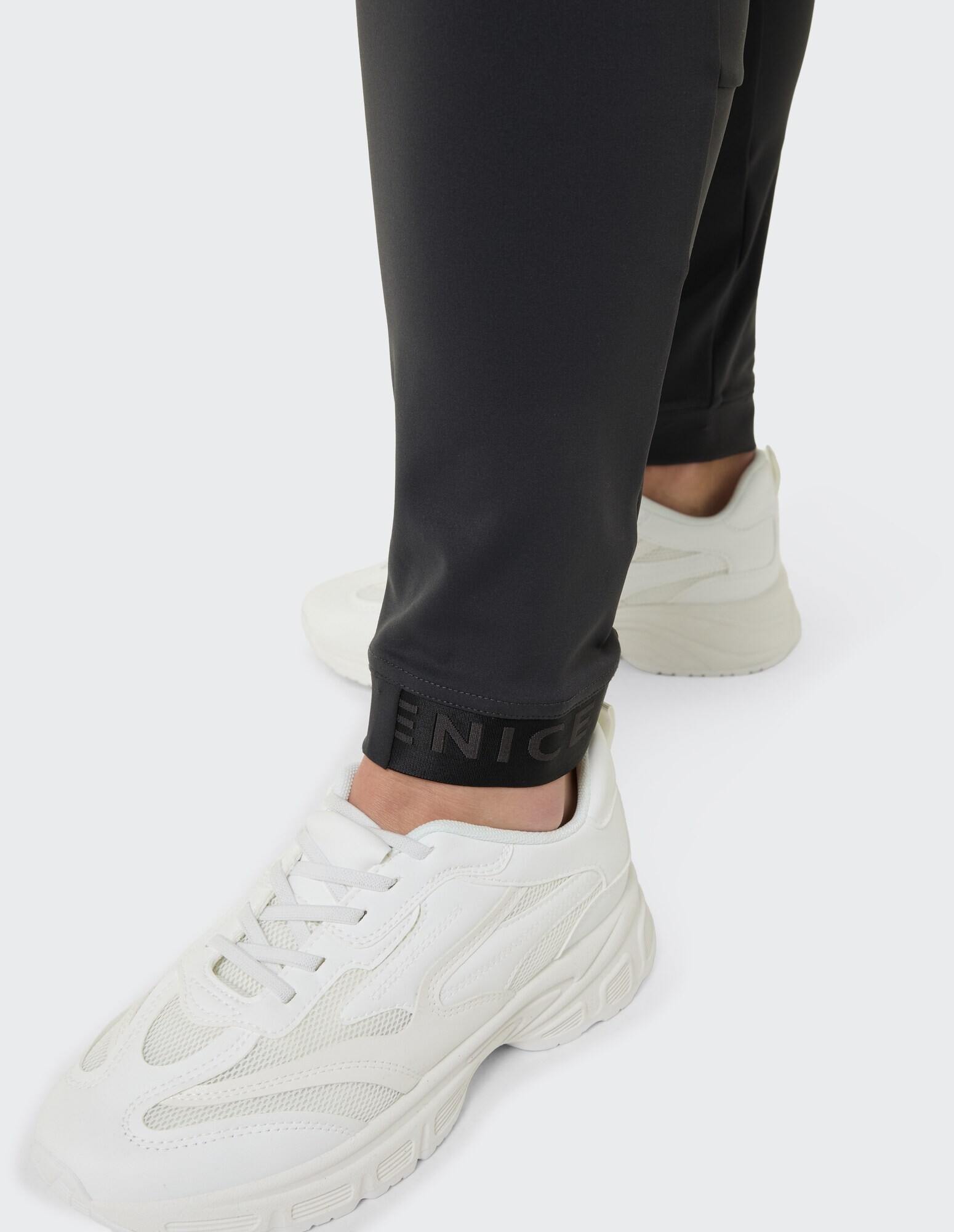 Nahaufnahme einer schwarzen sportlichen Hose gepaart mit weißen Turnschuhen, perfekt für Freizeitkleidung.