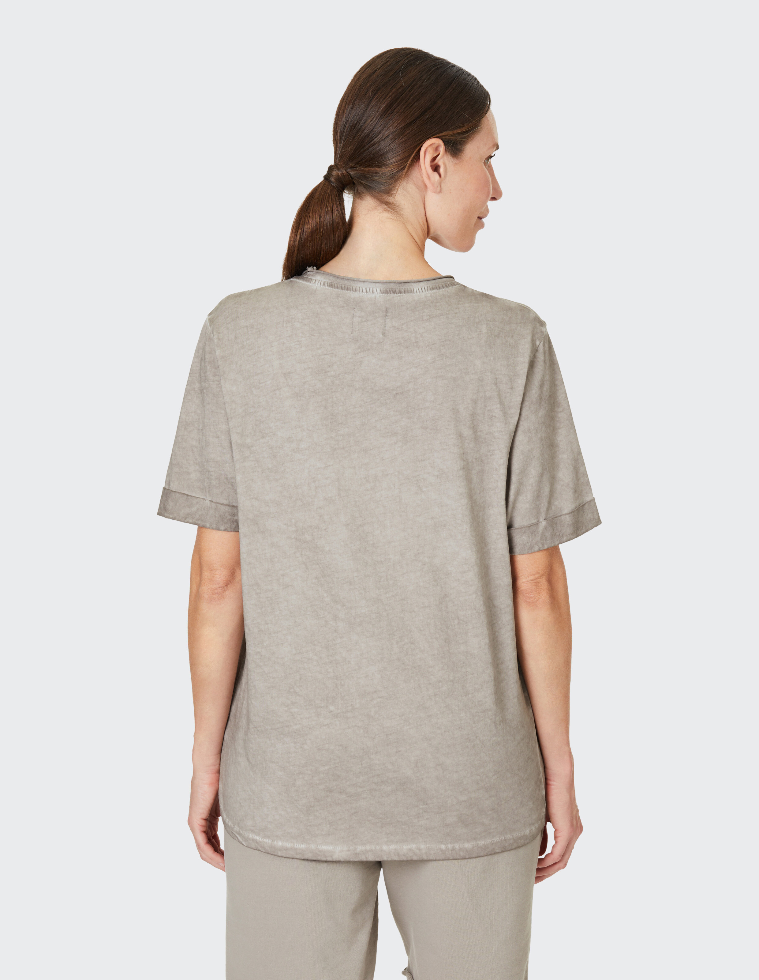 Frau trägt ein gemütliches, lässiges graues T-Shirt mit kurzen Ärmeln, Rückansicht.