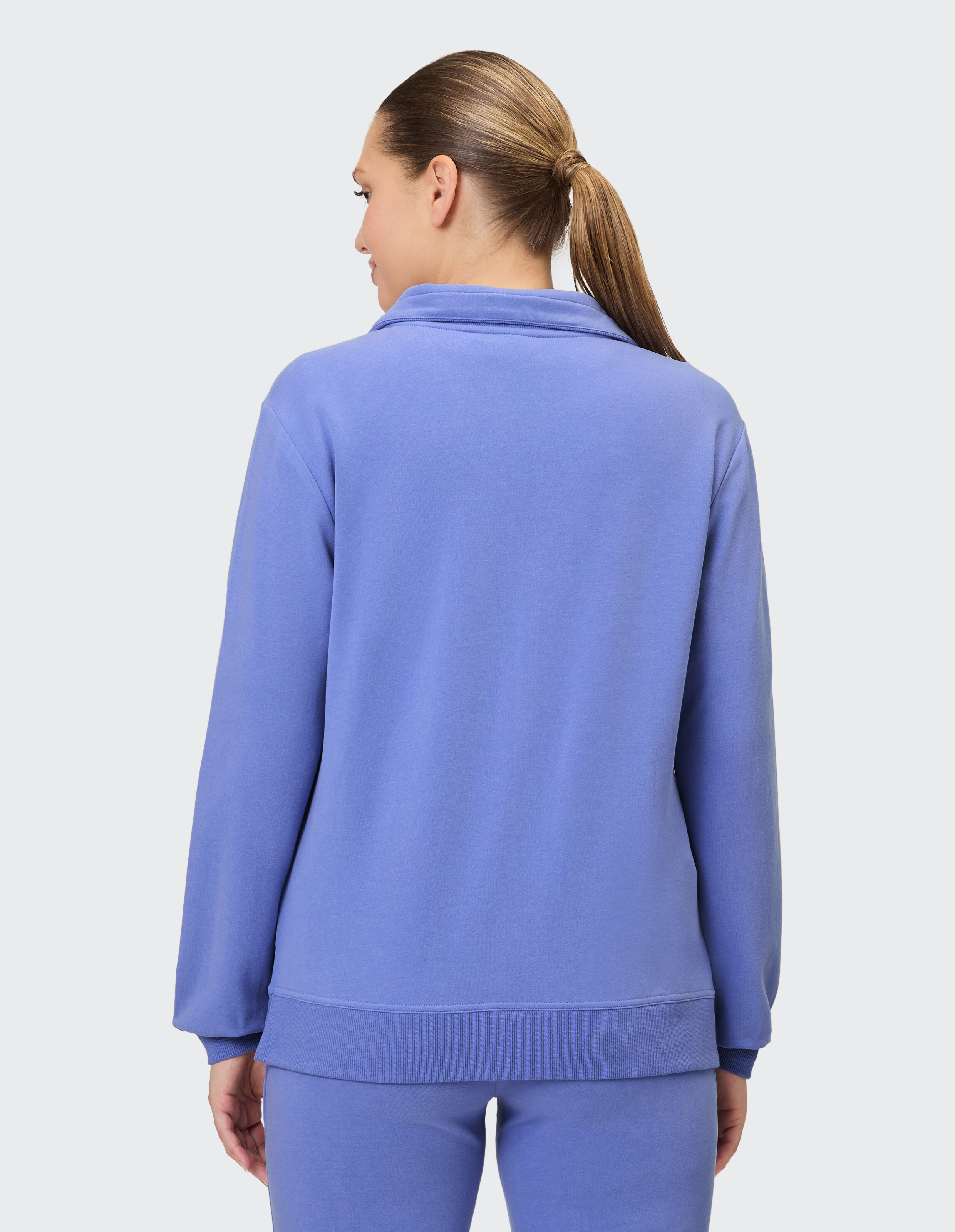 Rückansicht einer Frau in einem kuscheligen lavendelfarbenen Sweatshirt, perfekt für Freizeitkleidung.