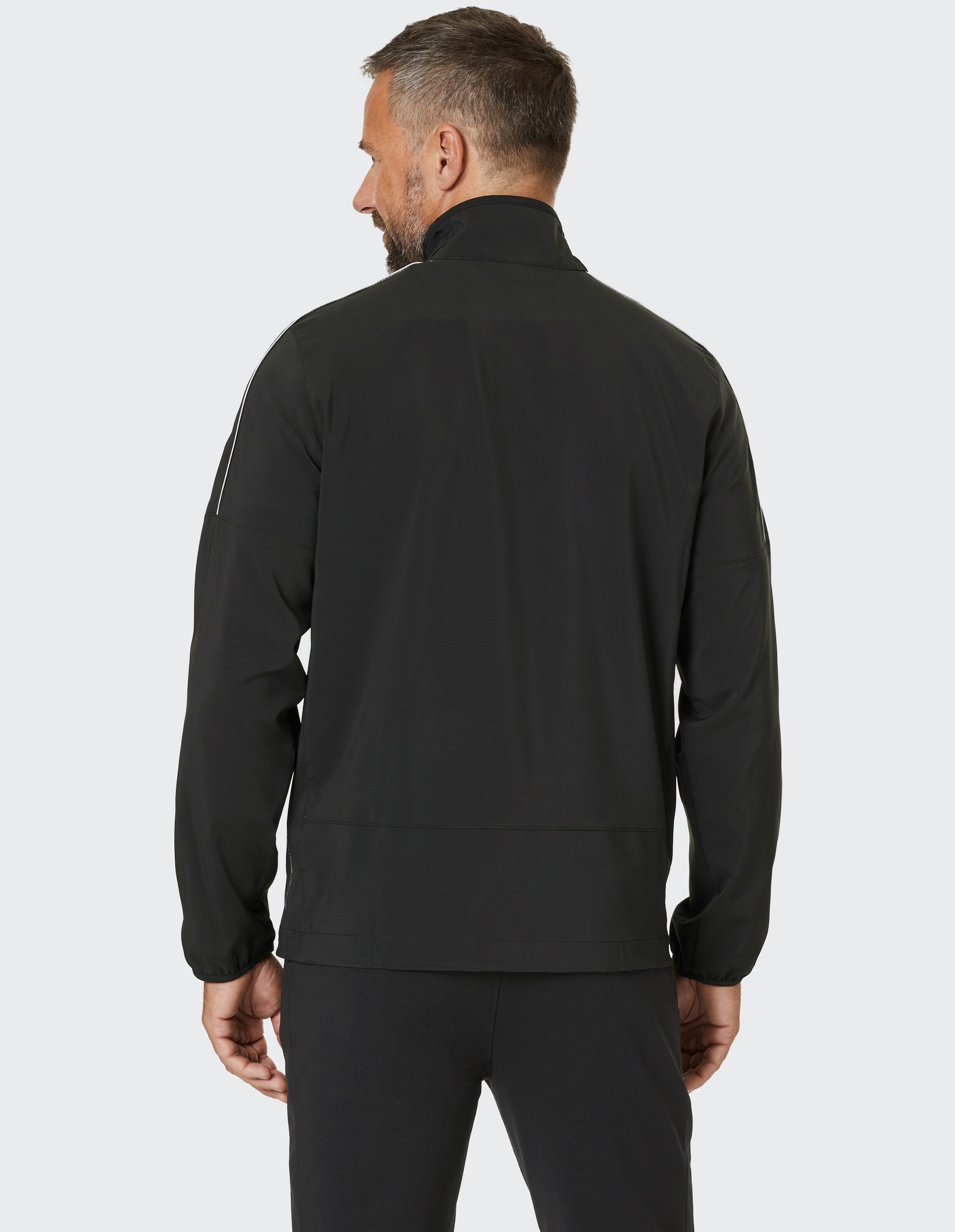 Eine schwarze Jacke mit weißem Reißverschluss und Paspeln, hohem Kragen und zwei Taschen mit Reißverschluss auf der Vorderseite.