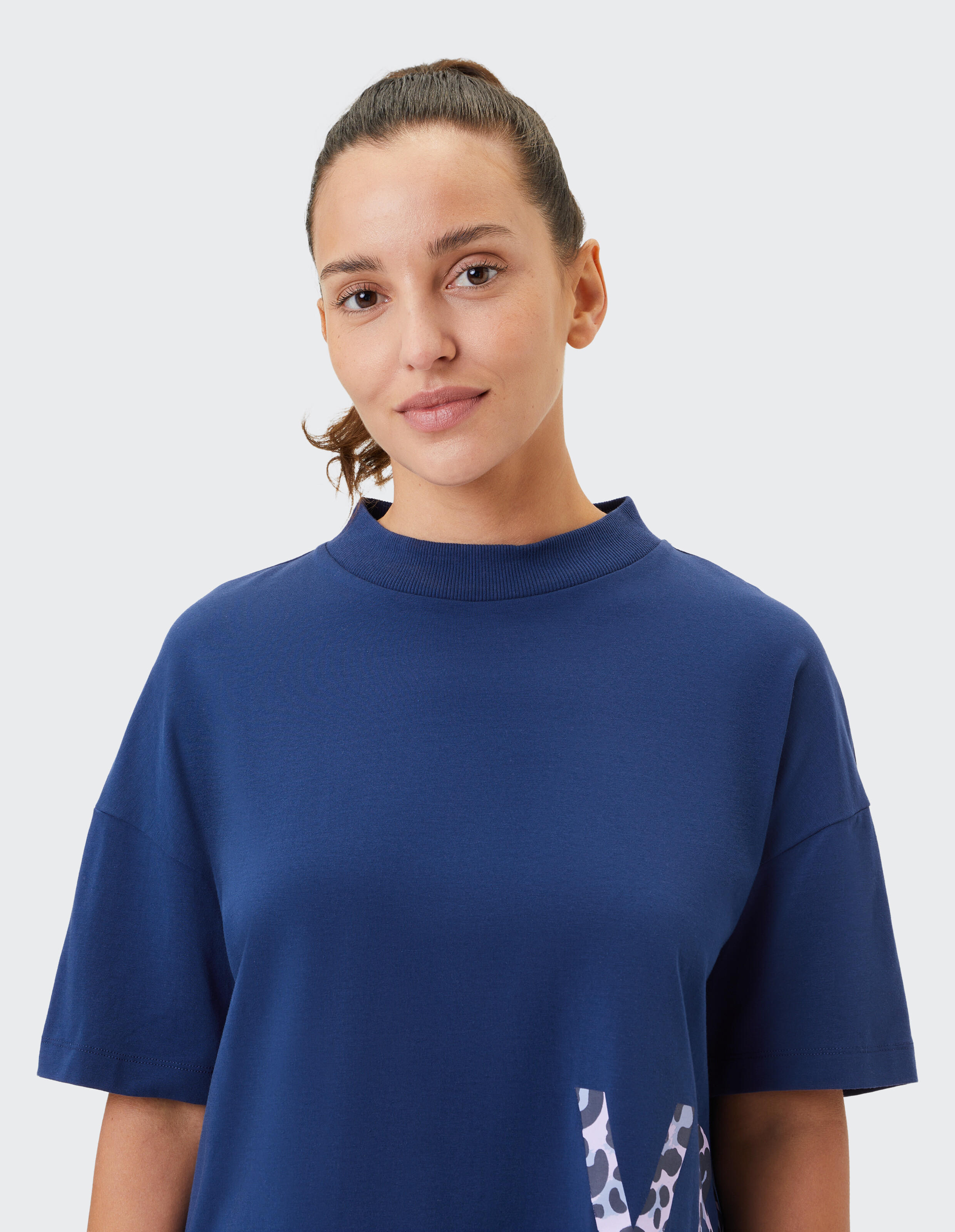Frau trägt ein gemütliches, marineblaues, übergroßes T-Shirt mit Stehkragen für lässige Lounge-Kleidung.
