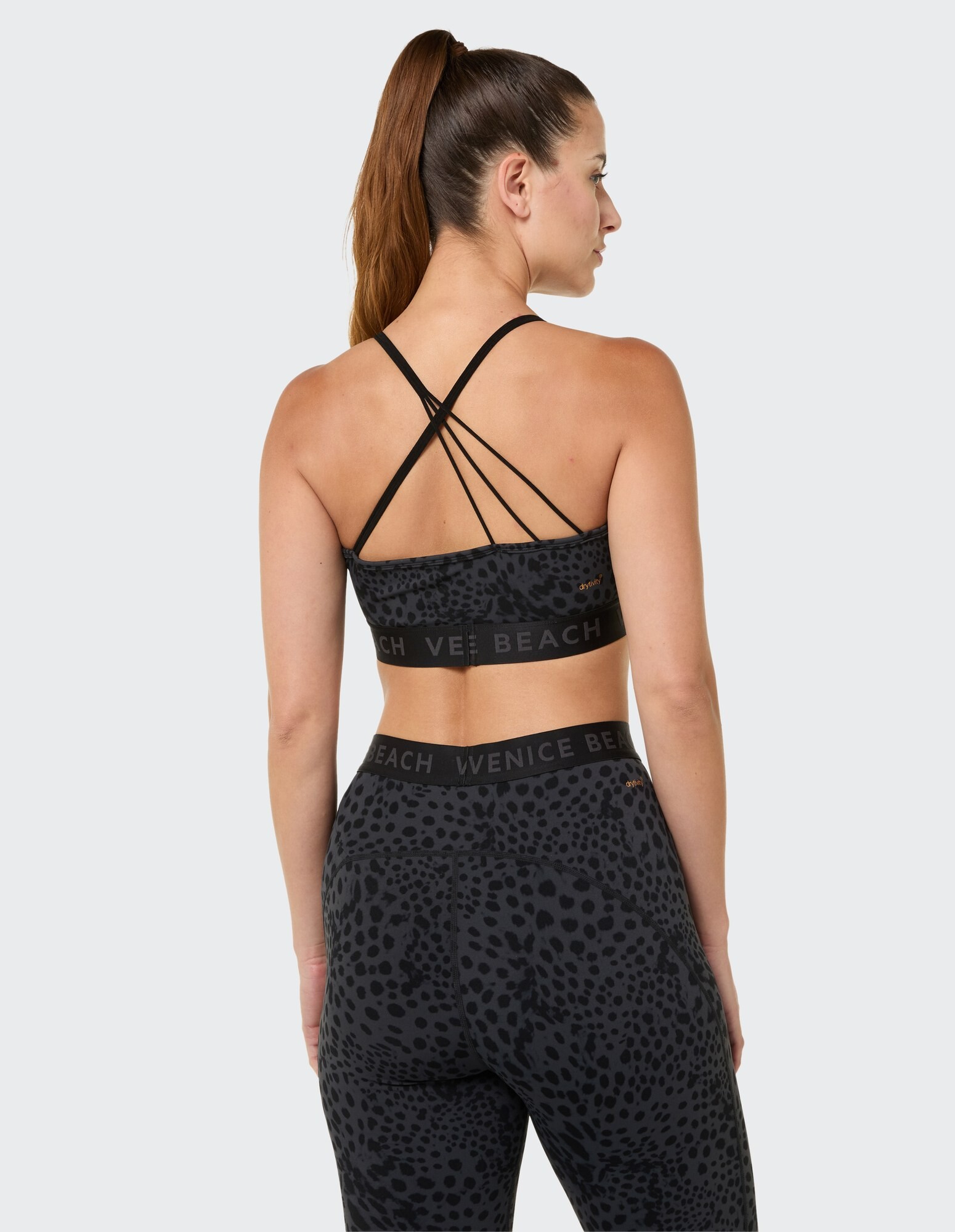 Rückansicht einer Frau in einem schwarzen Sport-BH mit Leopardenmuster und Leggings.