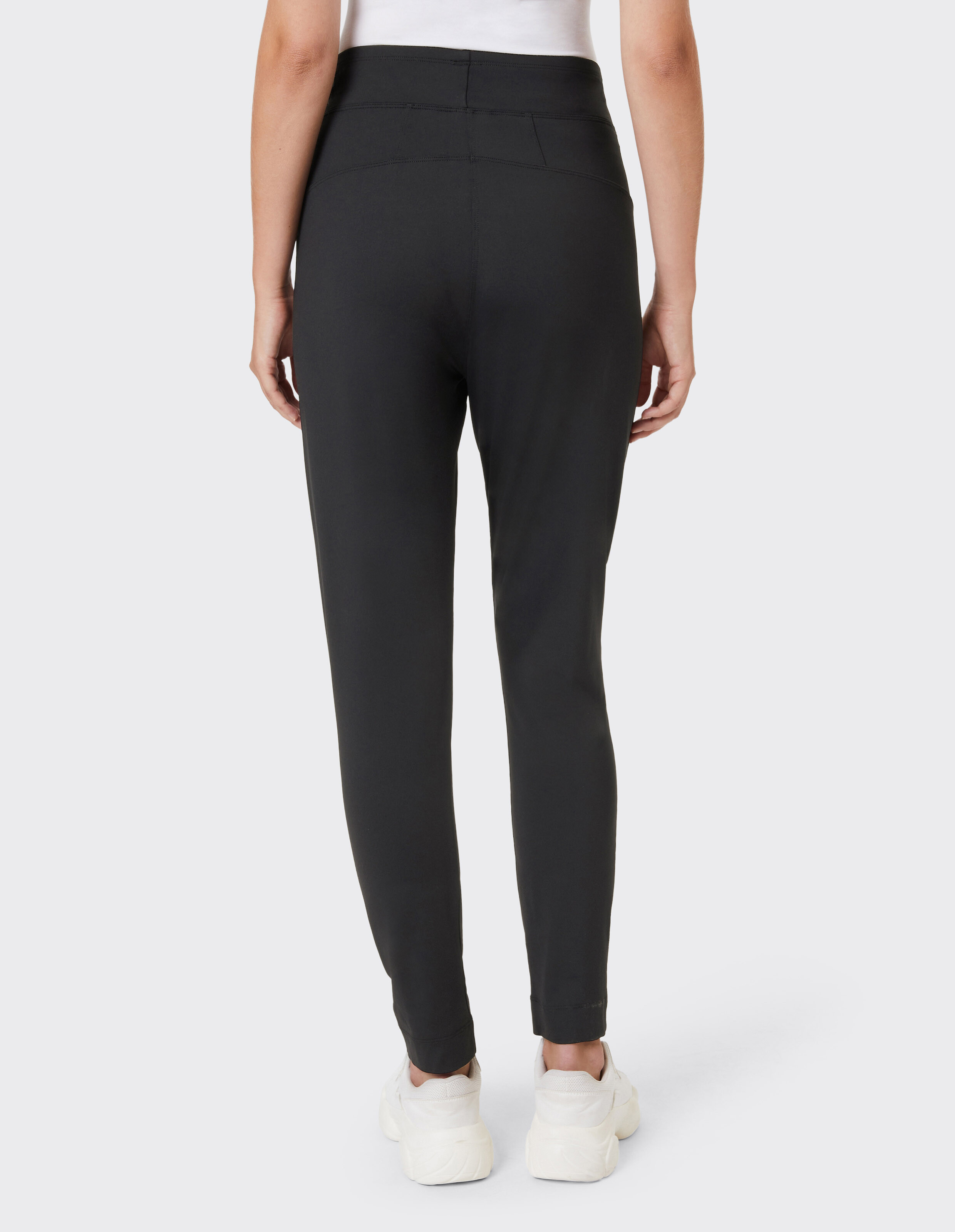 Rückansicht einer schwarzen Slim-Fit-Freizeithose gepaart mit weißen Turnschuhen.