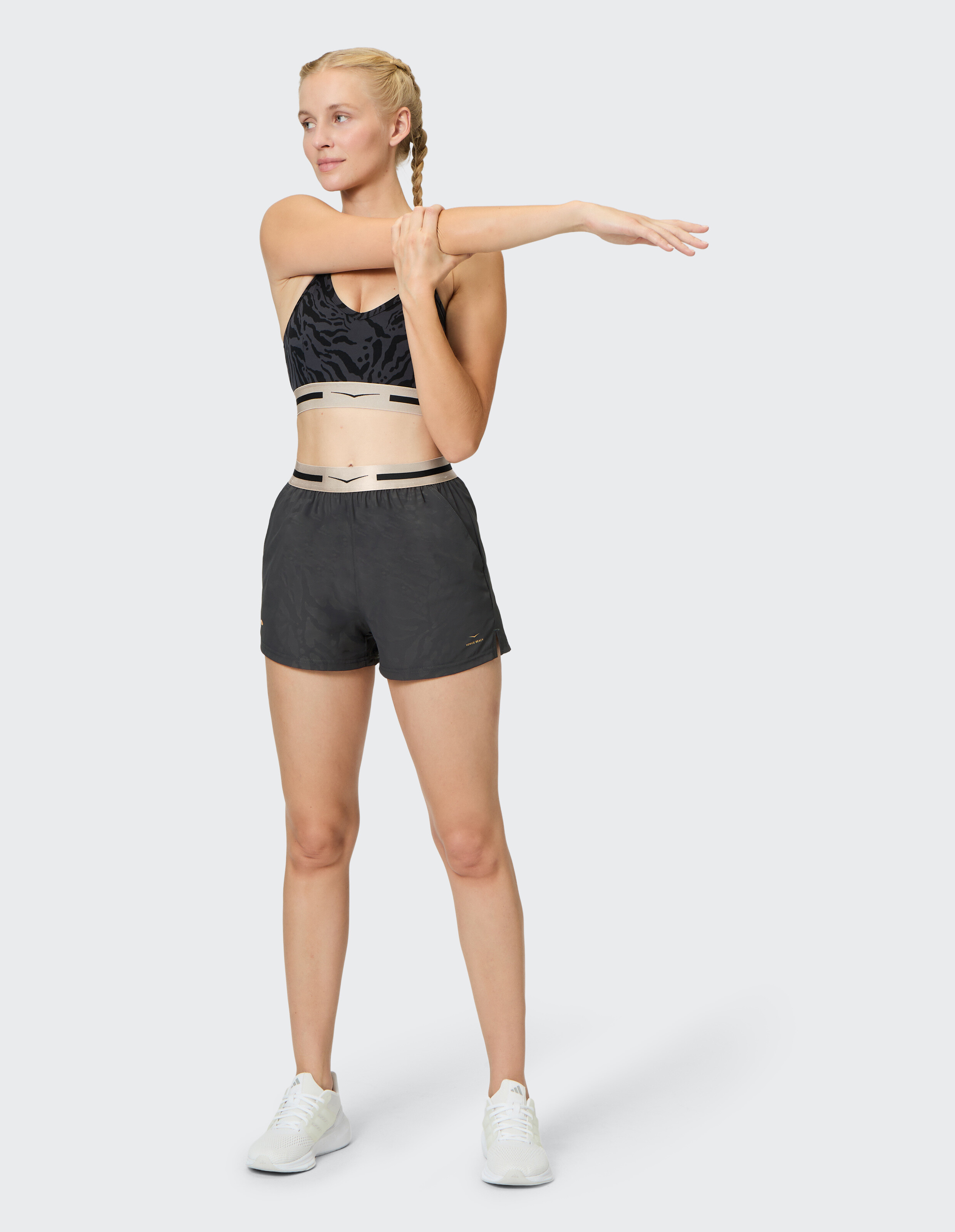 Frau in schwarz gemustertem Sport-BH und dehnbaren Shorts, gemütliche Aktivkleidung.