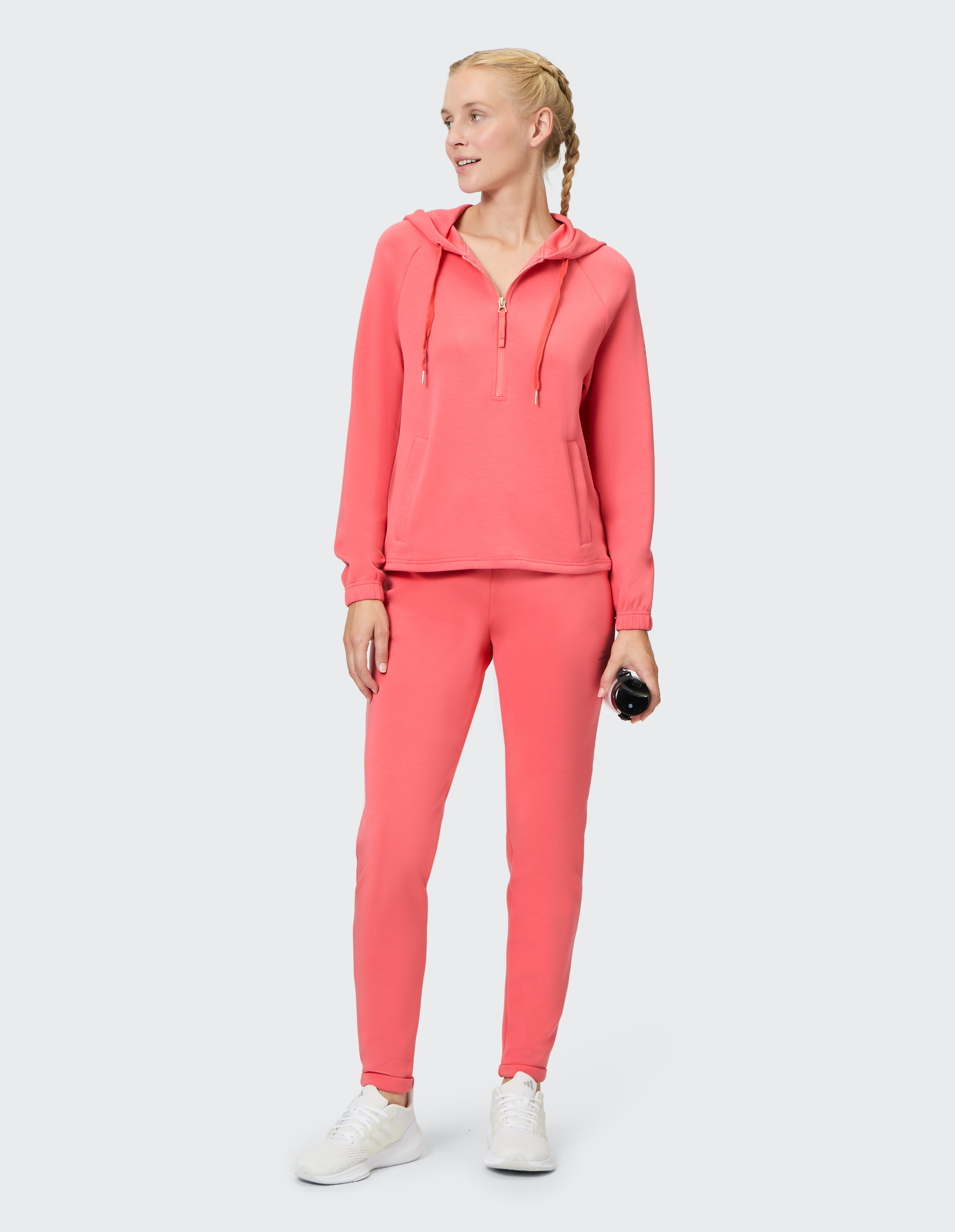 Frau in einem rosa Kapuzenpullover mit Reißverschluss und passenden Jogginghosen, perfekt für Freizeitkleidung.