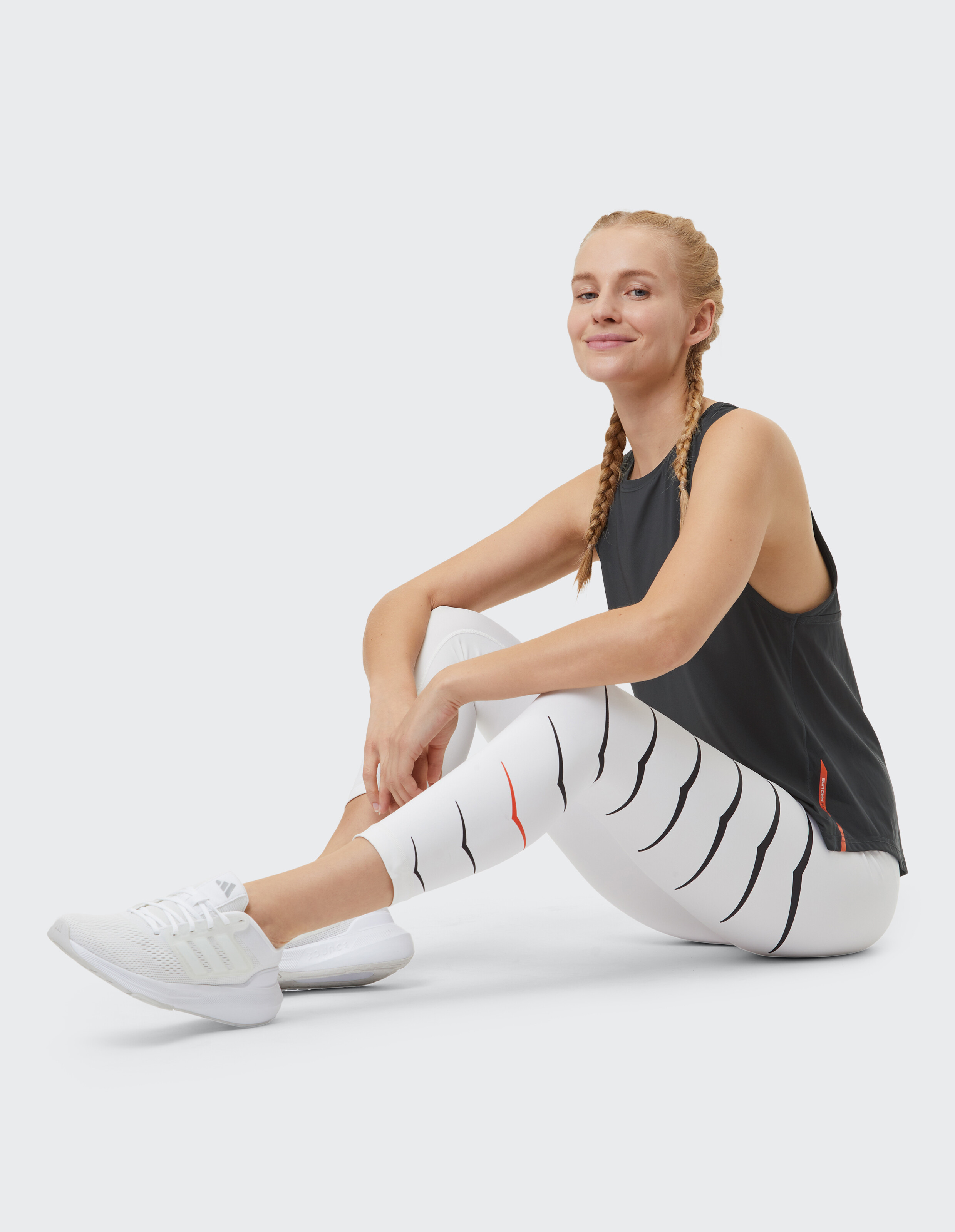 Frau trägt ein schwarzes Tanktop von Venice Beach und gemusterte Leggings für lässige Aktivkleidung.