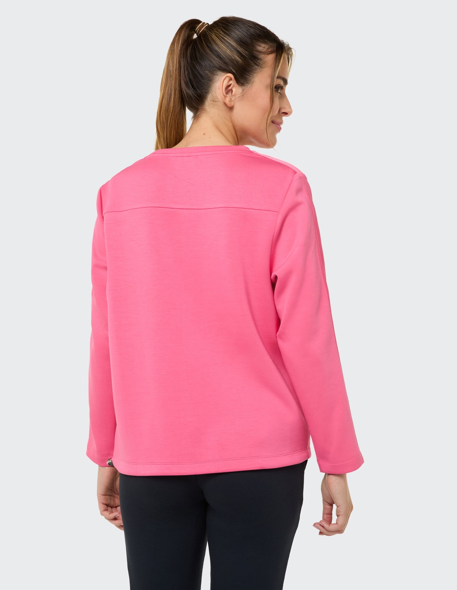 Rückansicht einer Frau in einem rosa lässigen Sweatshirt, perfekt zum Entspannen.