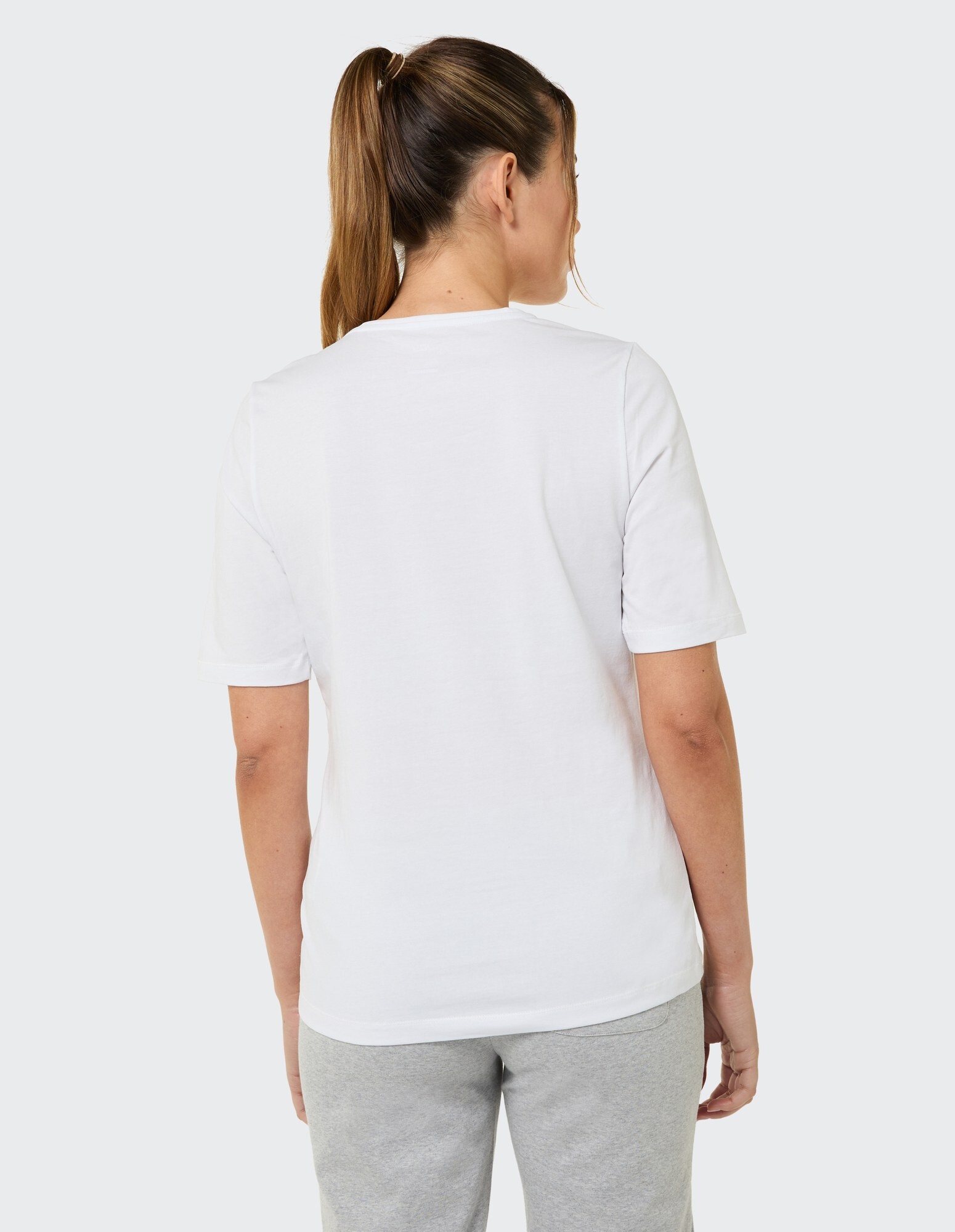 Rückansicht einer Frau, die ein weißes Freizeit-T-Shirt und eine graue Jogginghose trägt.