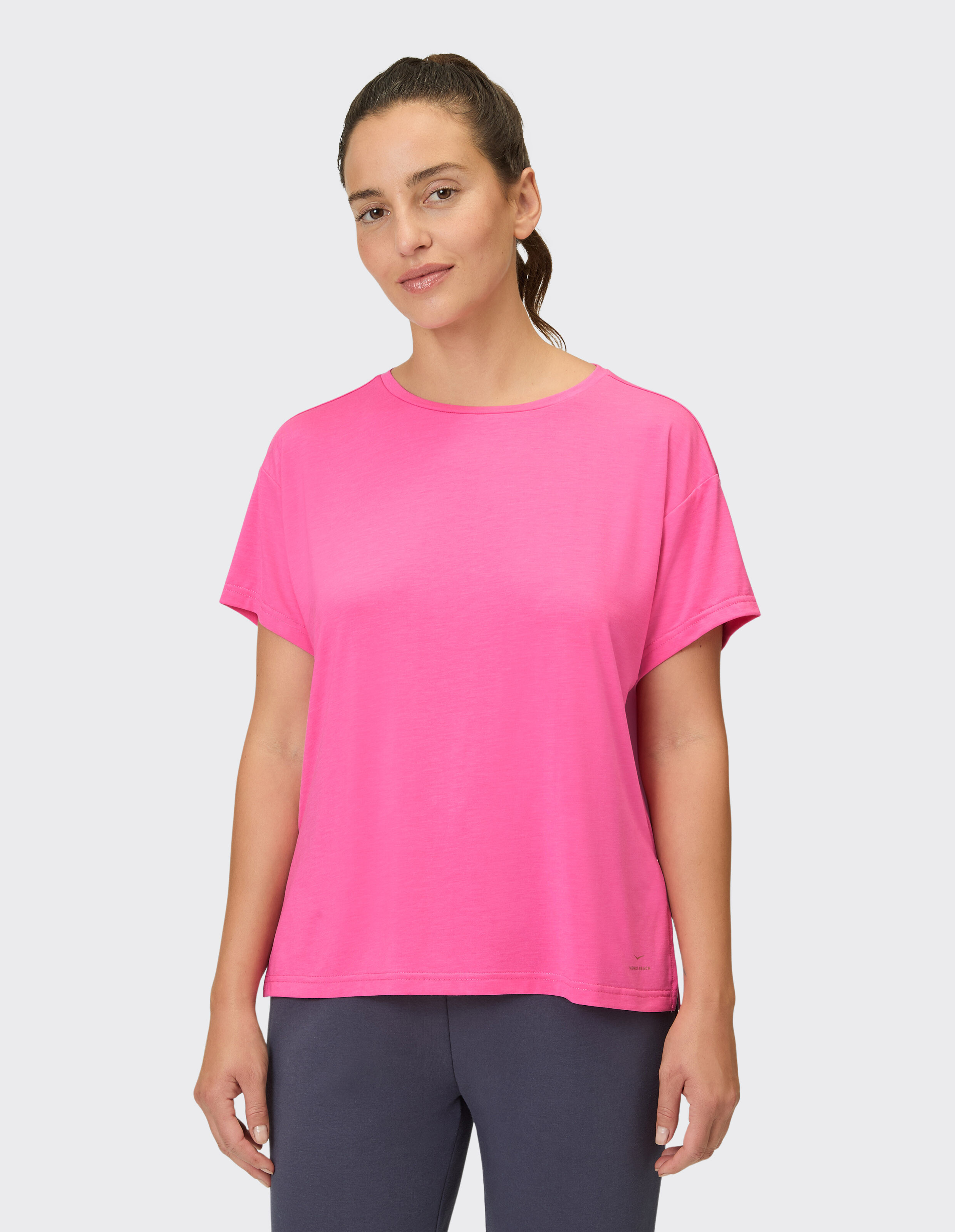 Frau trägt ein leuchtend rosa lässiges T-Shirt, perfekt zum Faulenzen oder Brunch.