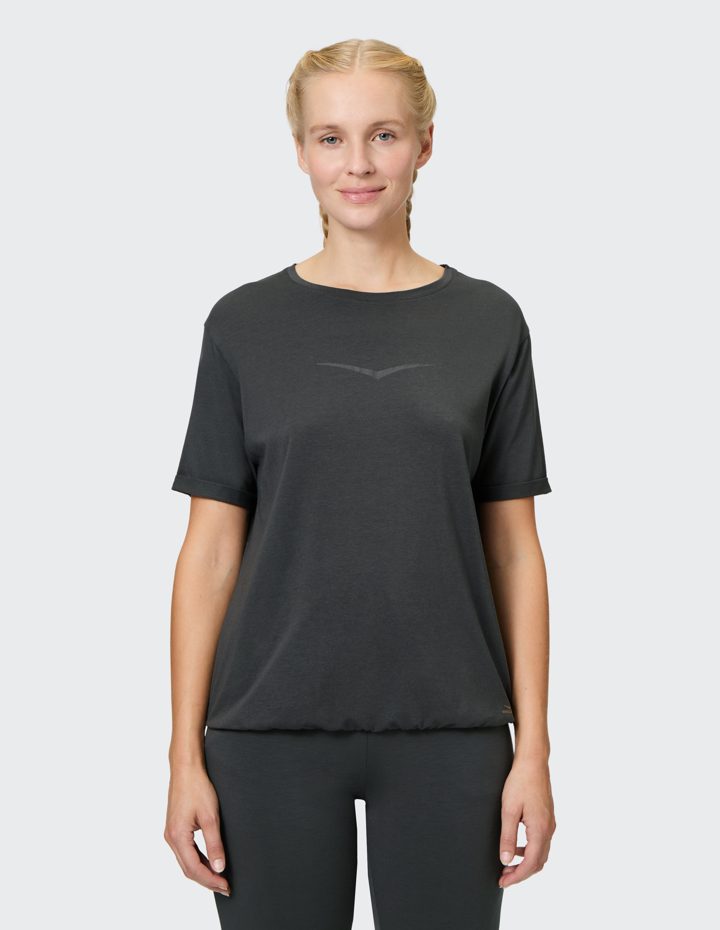 Frau trägt ein dunkelgraues Freizeit-T-Shirt mit kurzen Ärmeln und lockerer Passform.