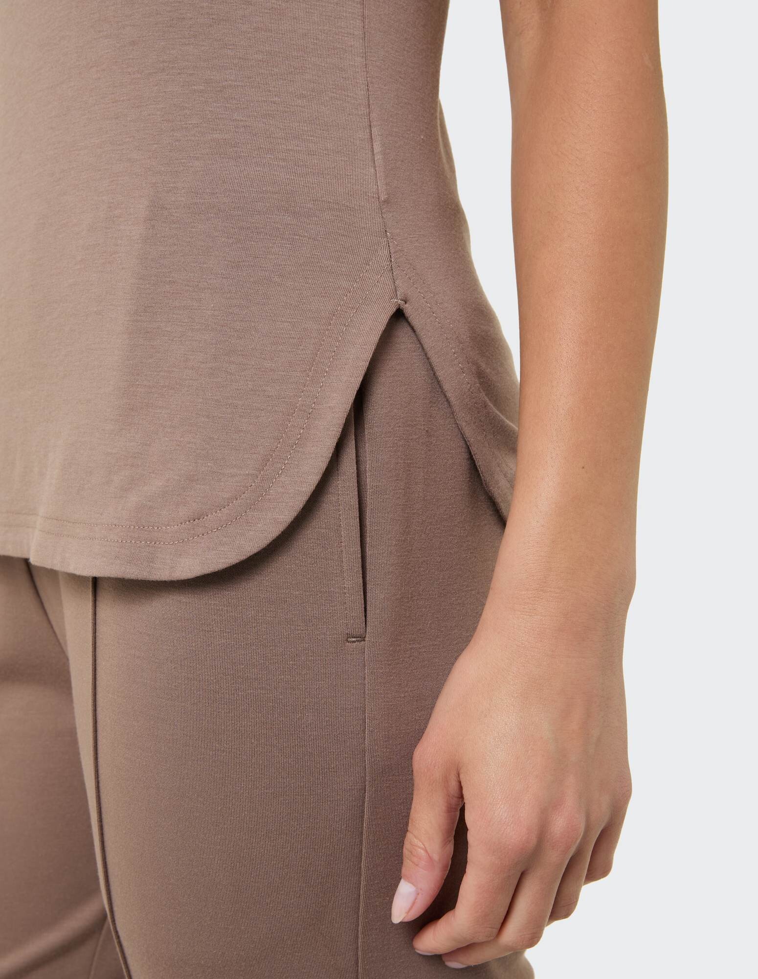 Nahaufnahme eines kuscheligen taupefarbenen Oberteils mit Seitenschlitzen, gepaart mit einer passenden Hose.