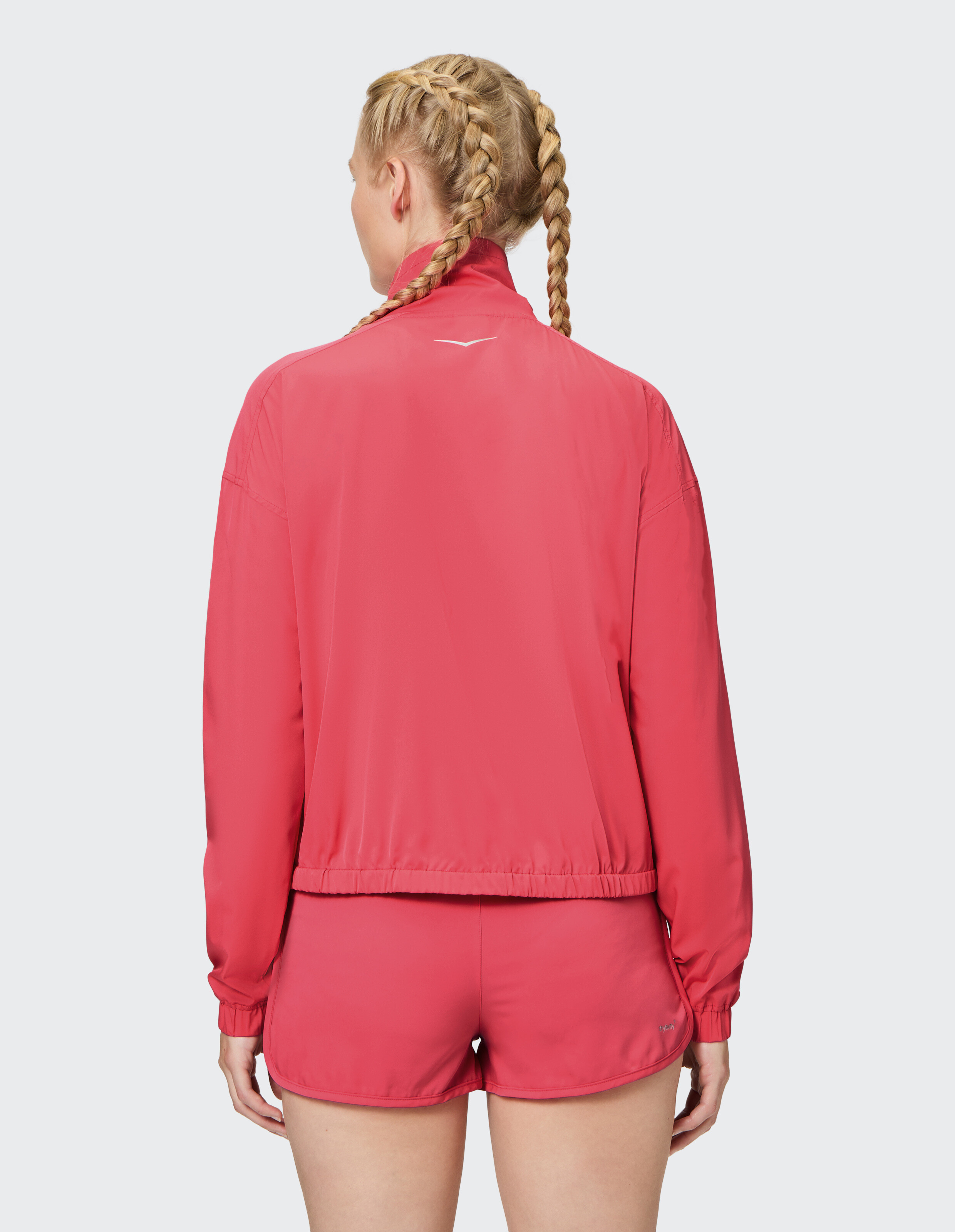 Rückansicht einer Frau in einer rosa leichten Jacke und passenden Shorts.