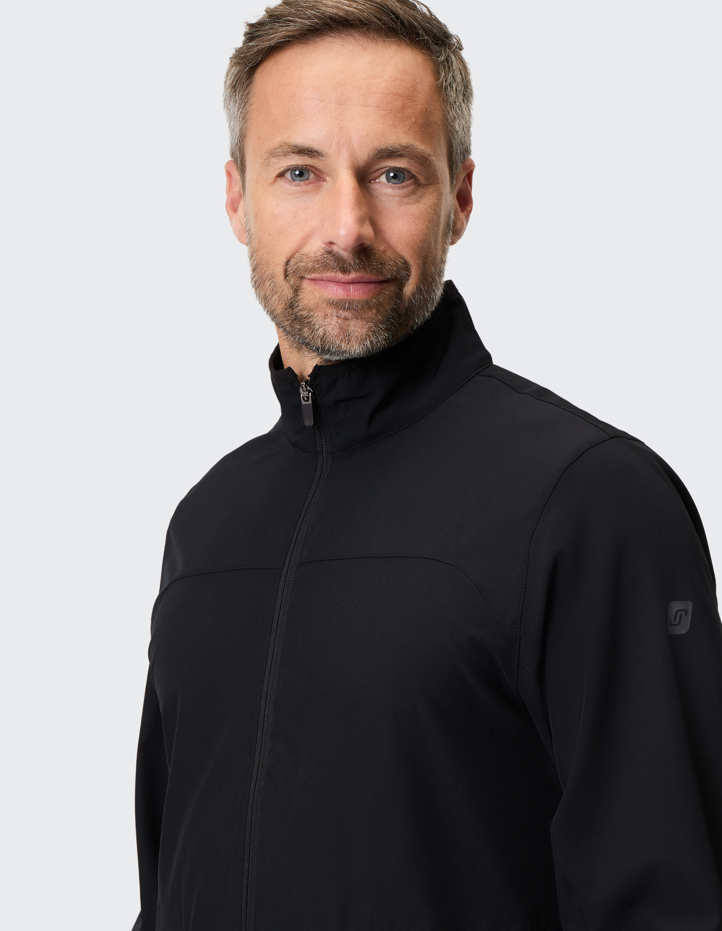 Mann trägt eine schwarze ELBSAND-Reißverschlussjacke mit hohem Kragen für lässigen Stil.