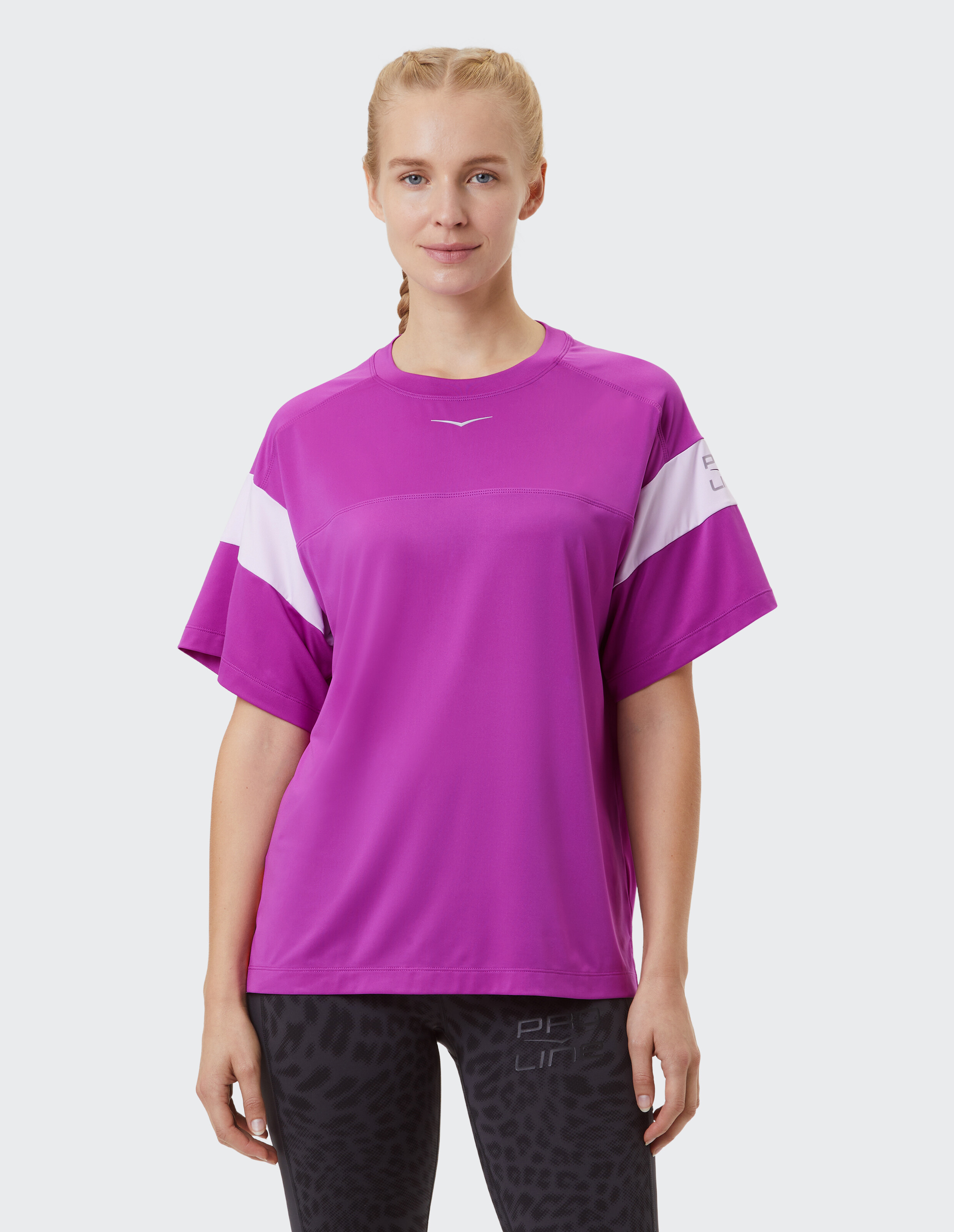 Frau trägt ein lockeres magentafarbenes Freizeit-T-Shirt mit weißen Ärmelstreifen.