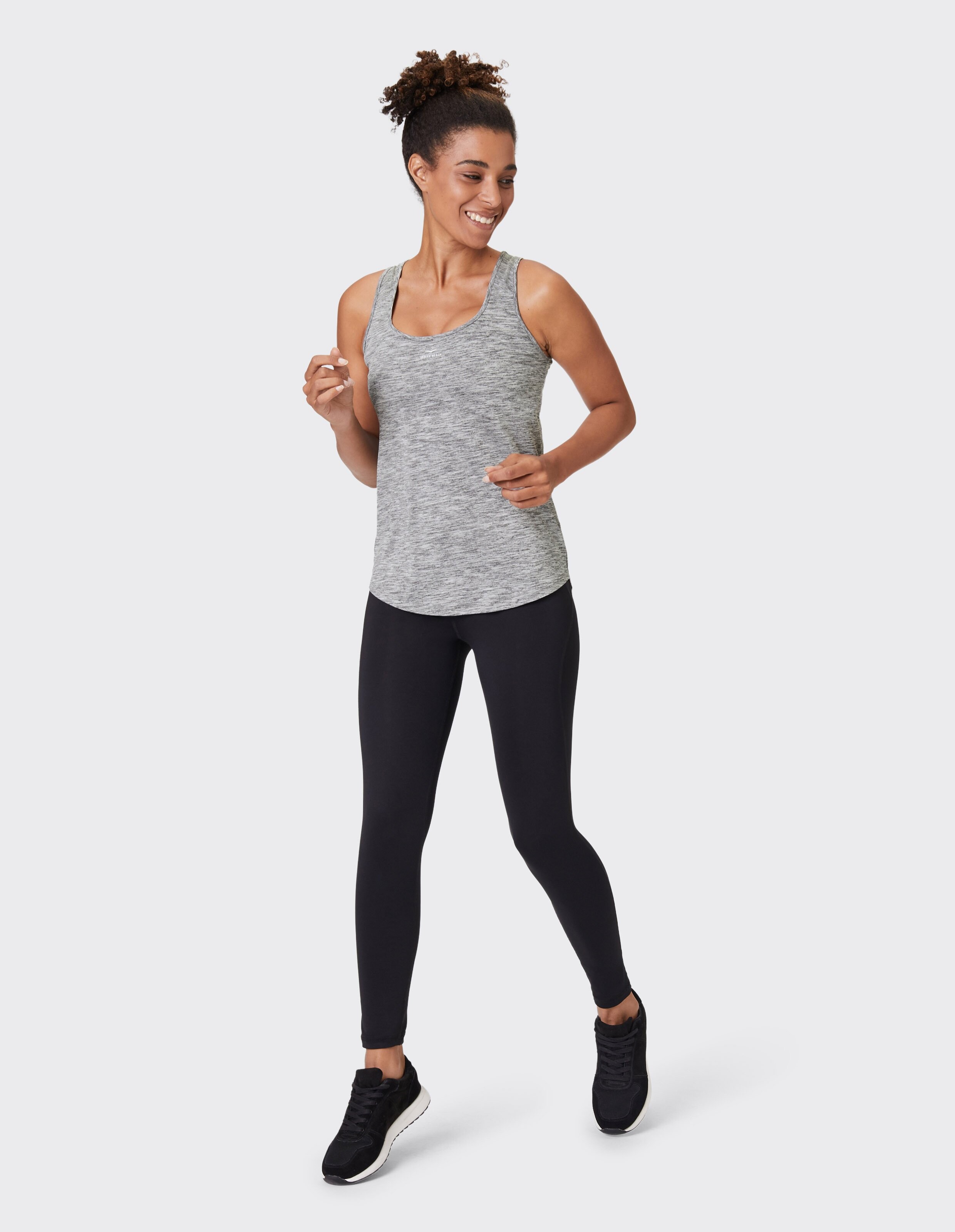 Frau trägt ein graues Venice Beach Tanktop Lou mit schwarzen Leggings für lässige Aktivkleidung.