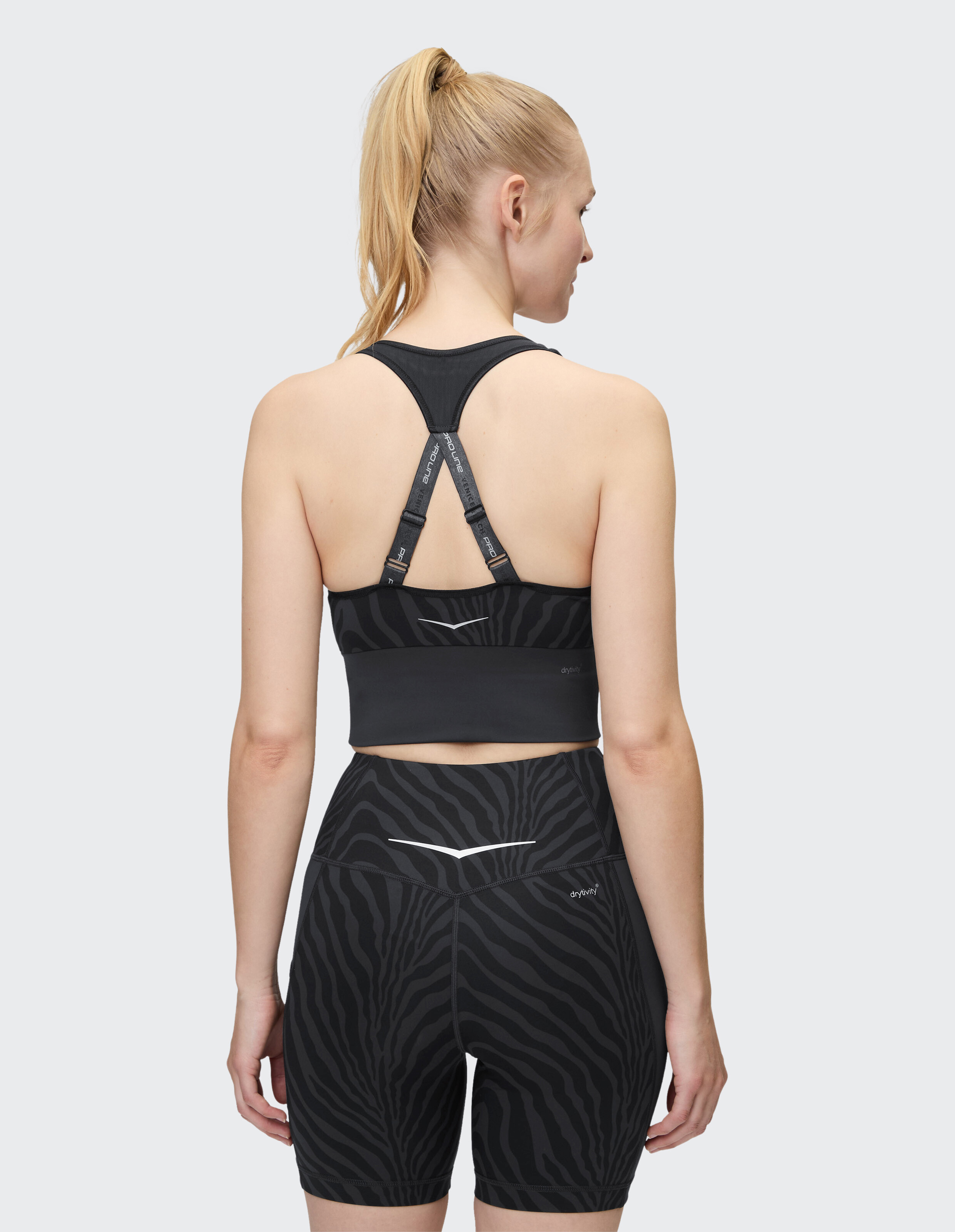 Frau trägt einen schwarzen Sport-BH mit Zebramuster und passende Bikershorts.