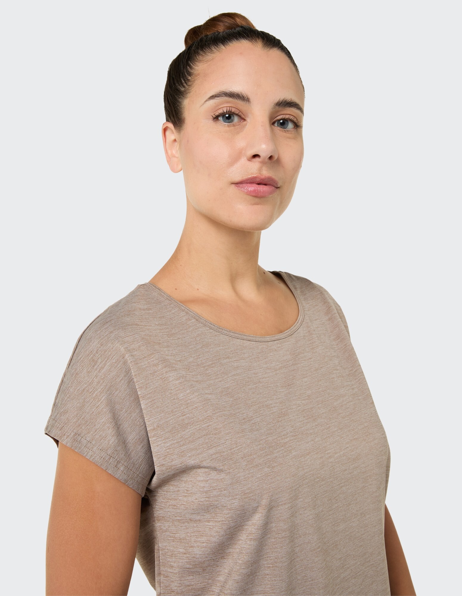 Nahaufnahme einer Frau in einem hellbraunen Freizeit-T-Shirt mit kurzen Ärmeln.