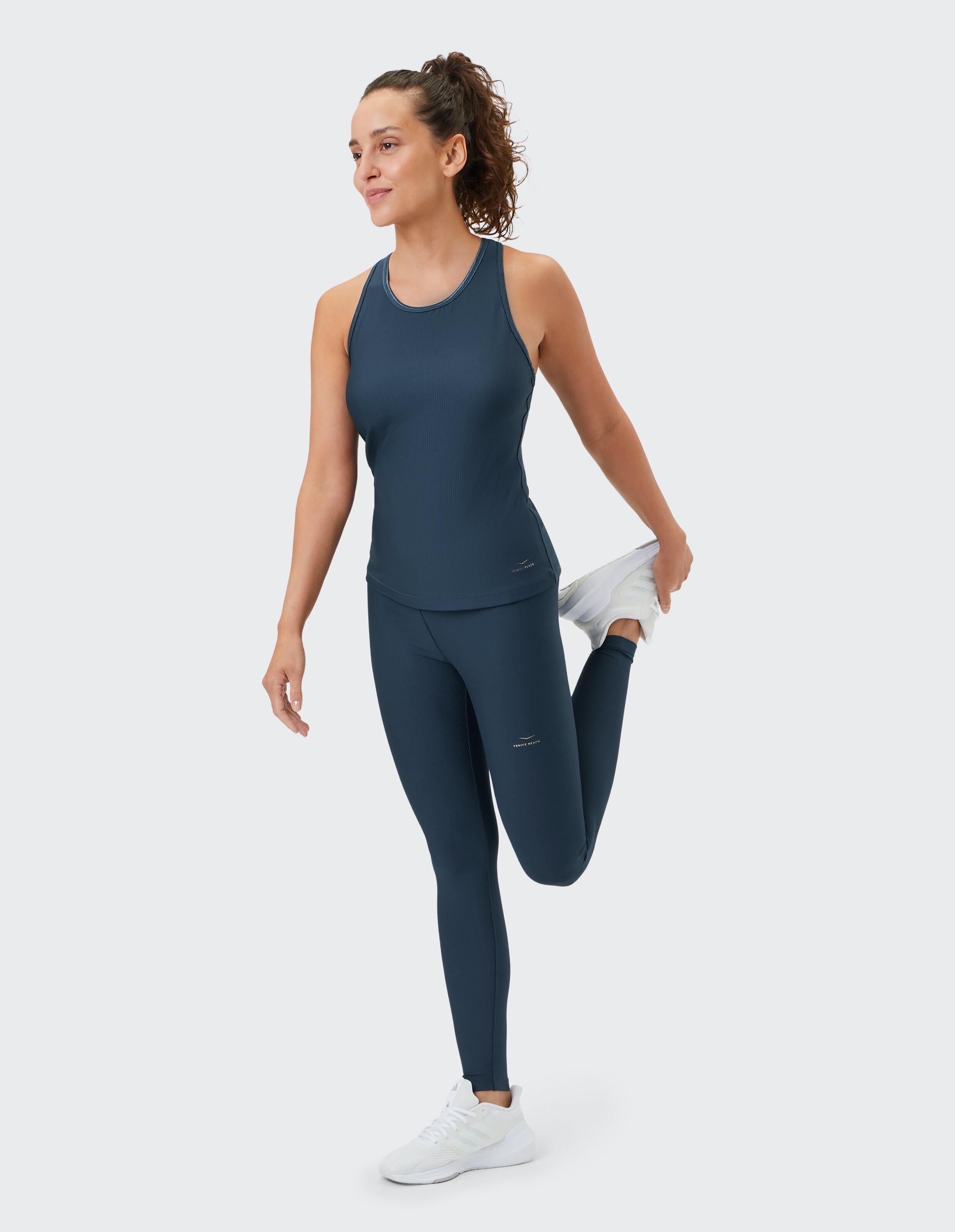 Frau in dunkelblauem, geripptem Tanktop und Stretch-Leggings, lässige Aktivkleidung.