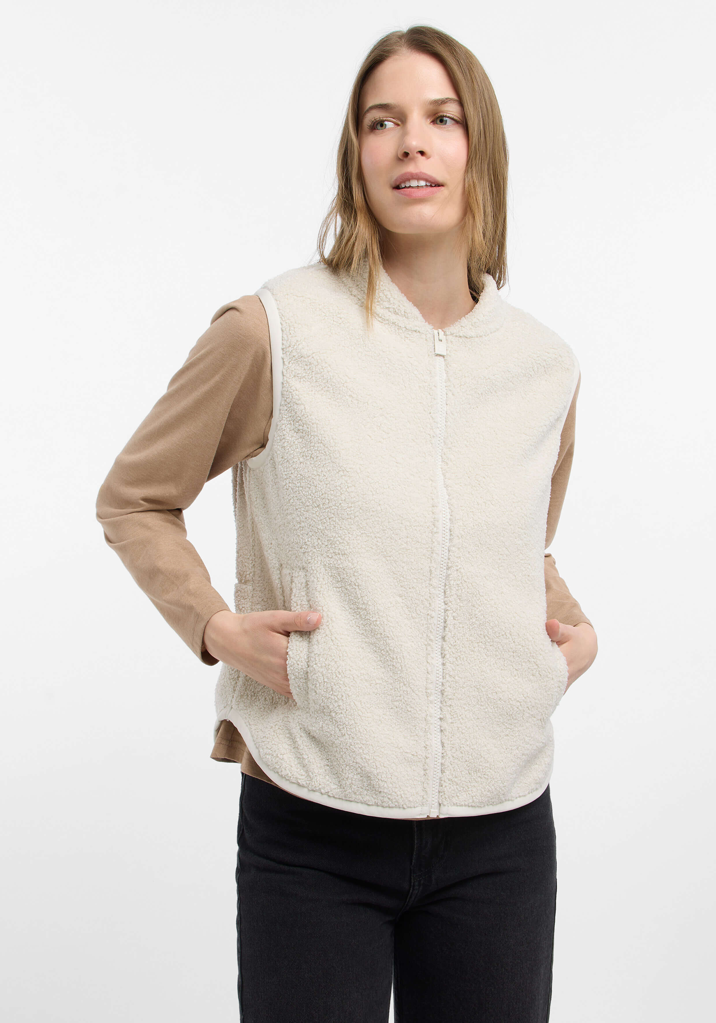 Frau trägt eine kuschelige cremefarbene Fleeceweste über einem beigen Langarmshirt.