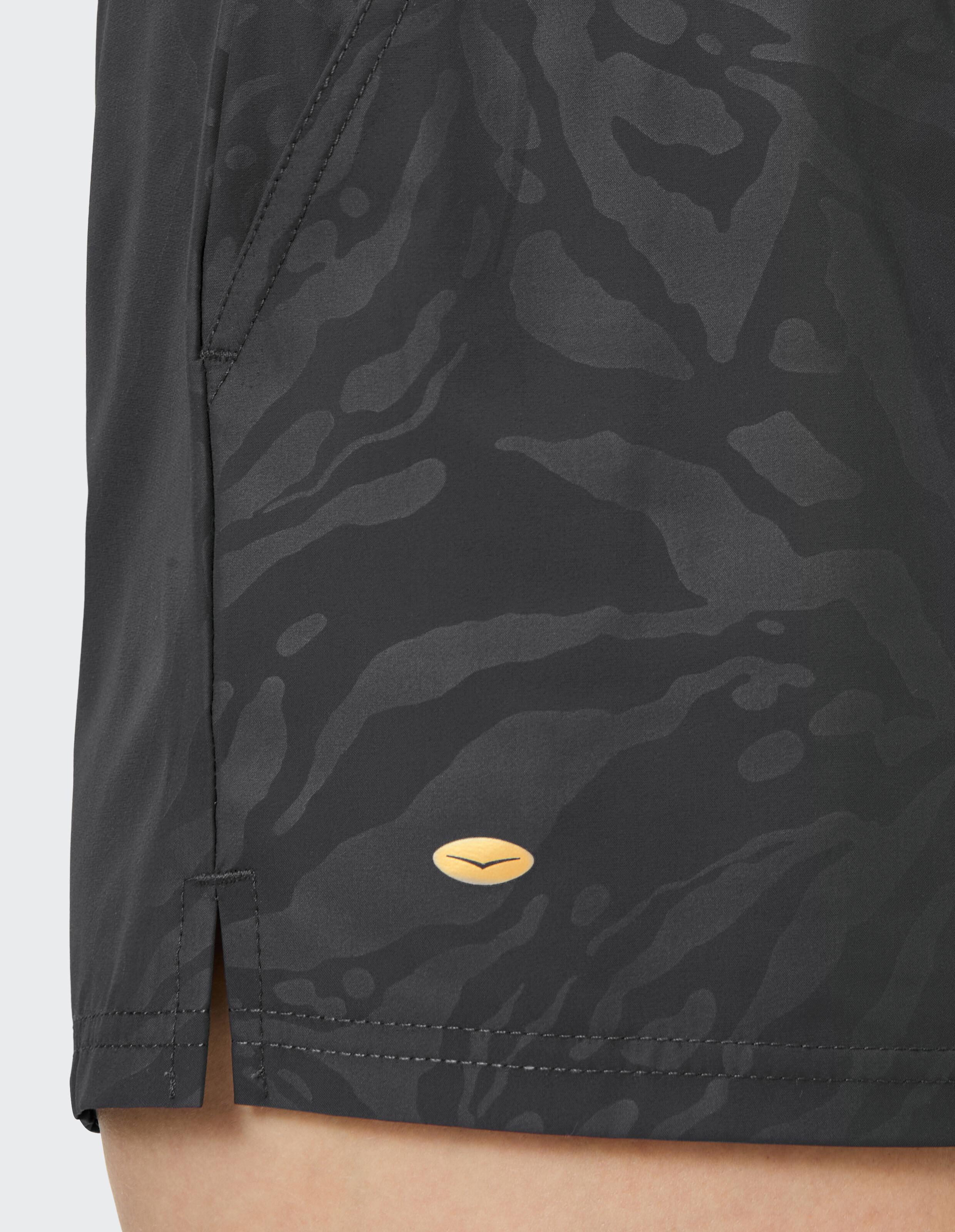 Nahaufnahme von schwarz gemusterten Shorts mit stylischem Schlitz und Logo-Detail.