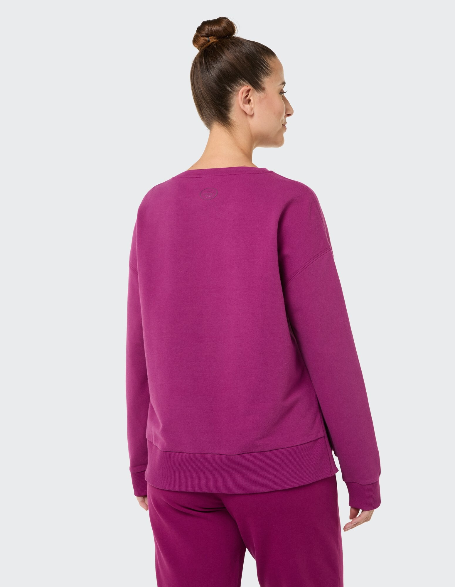 Rückansicht einer Frau in einem gemütlichen lila Sweatshirt und passender Hose.