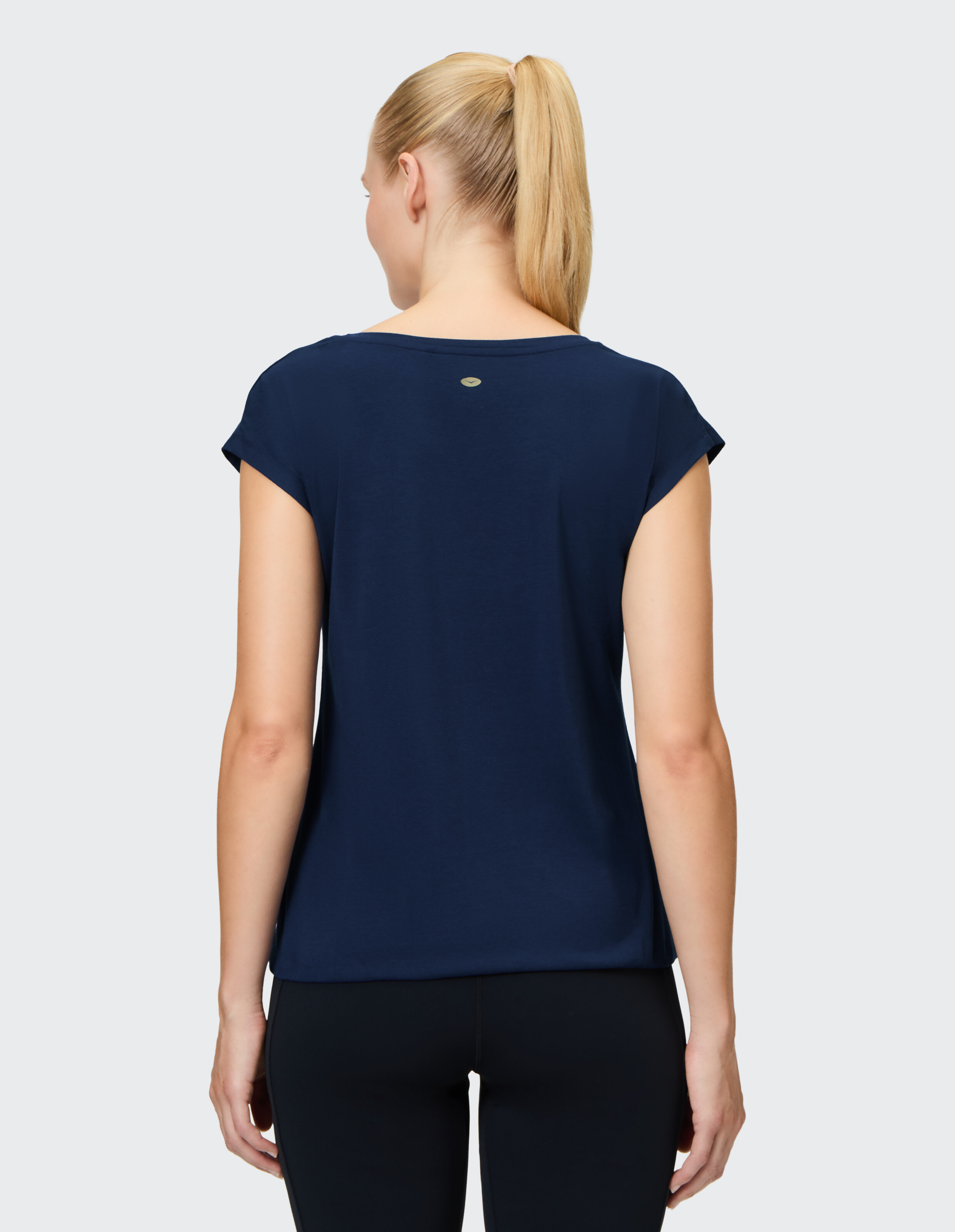 Rückansicht einer Frau, die ein dunkelblaues Freizeit-T-Shirt mit hochgekrempelten Ärmeln trägt.