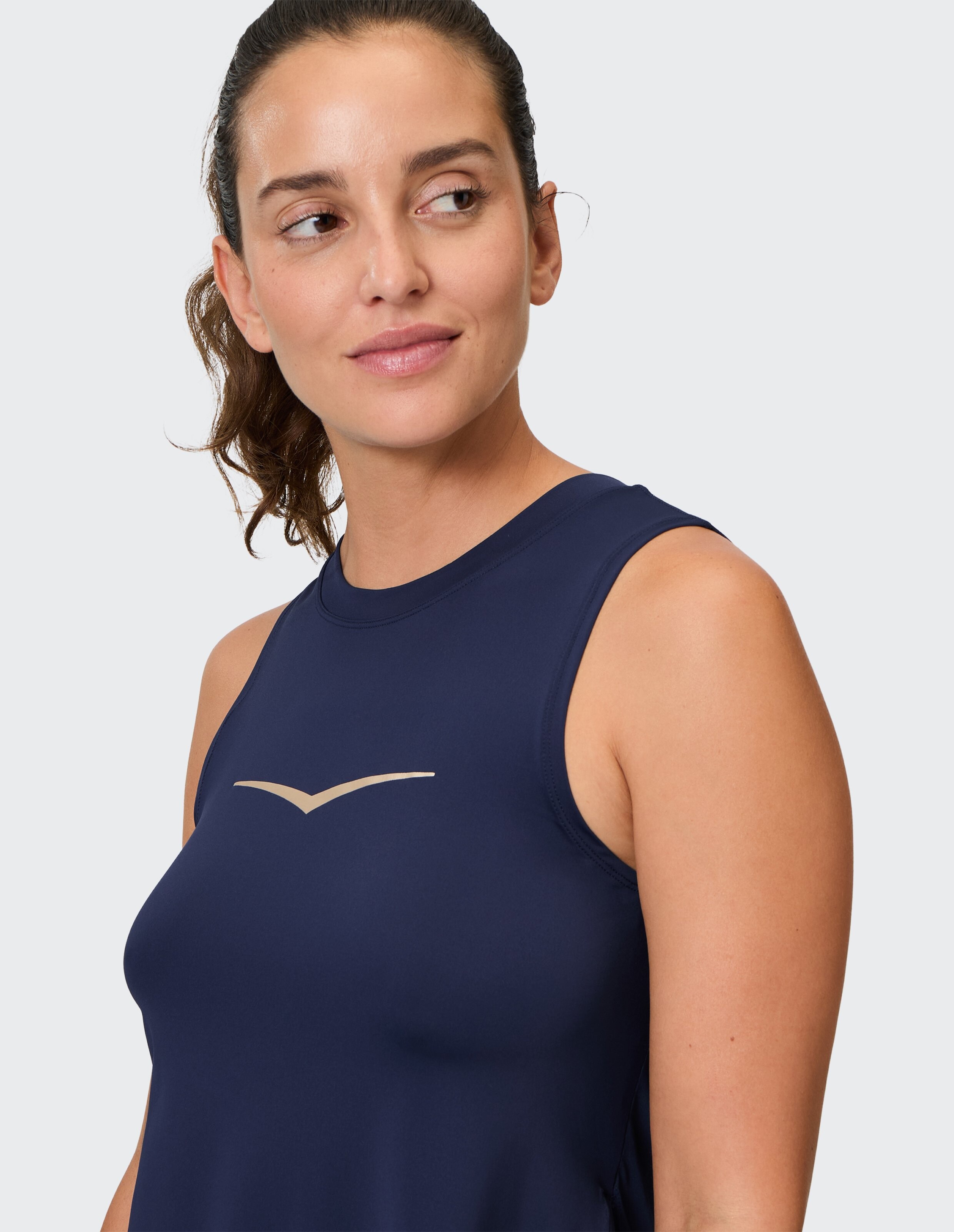 Frau in einem marineblauen ärmellosen Oberteil mit goldenem Logo, das einen lässigen Stil unterstreicht.