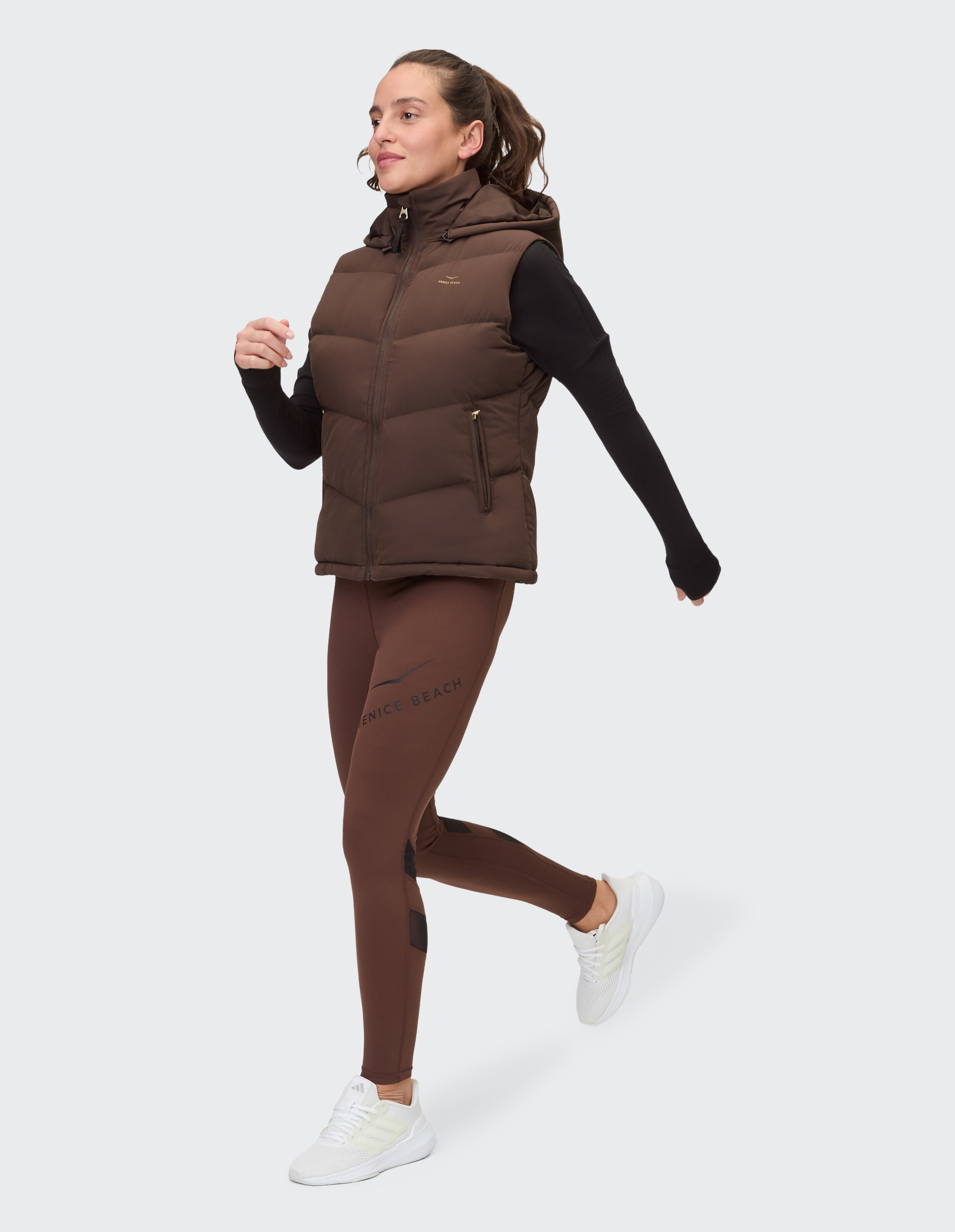 Frau trägt eine braune Steppweste und Leggings für einen gemütlichen, aktiven Casual-Look.