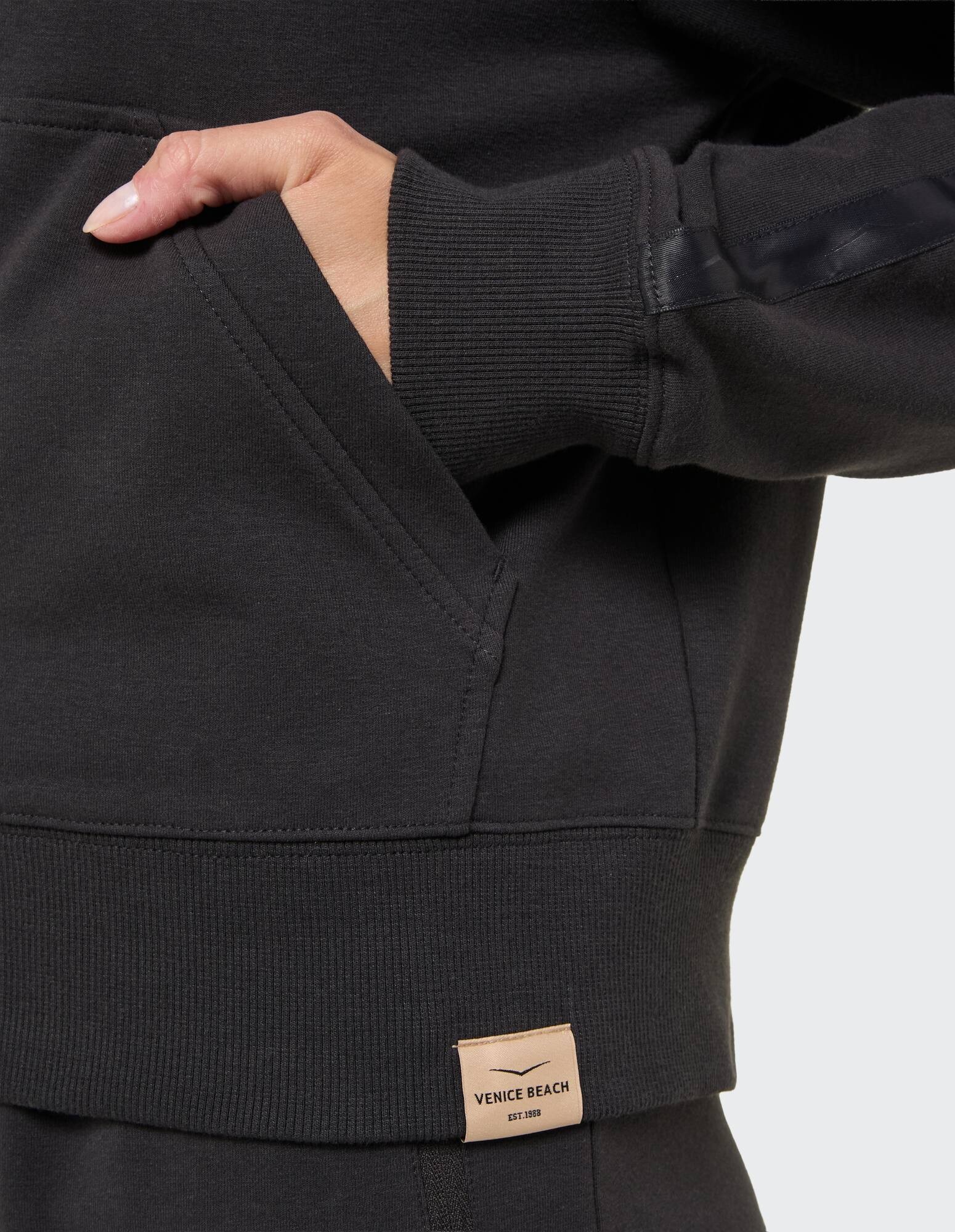 Nahaufnahme eines dunkelgrauen Sweatshirts mit gerippten Bündchen und einer Tasche.
