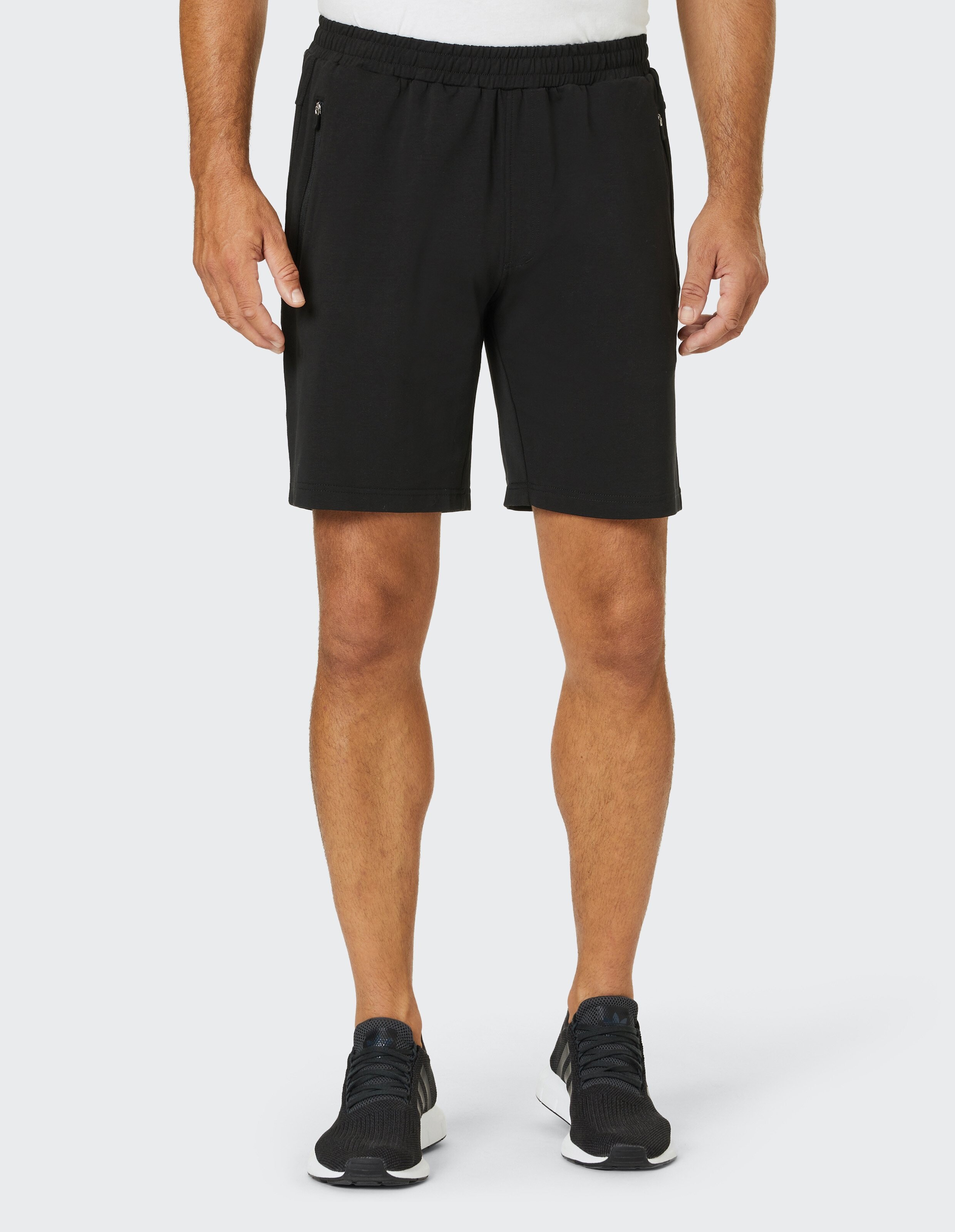 Schwarze Baumwoll-Shorts mit elastischem Bund und seitlichen Reißverschlusstaschen, schlichtes Design ohne sichtbare Logos.