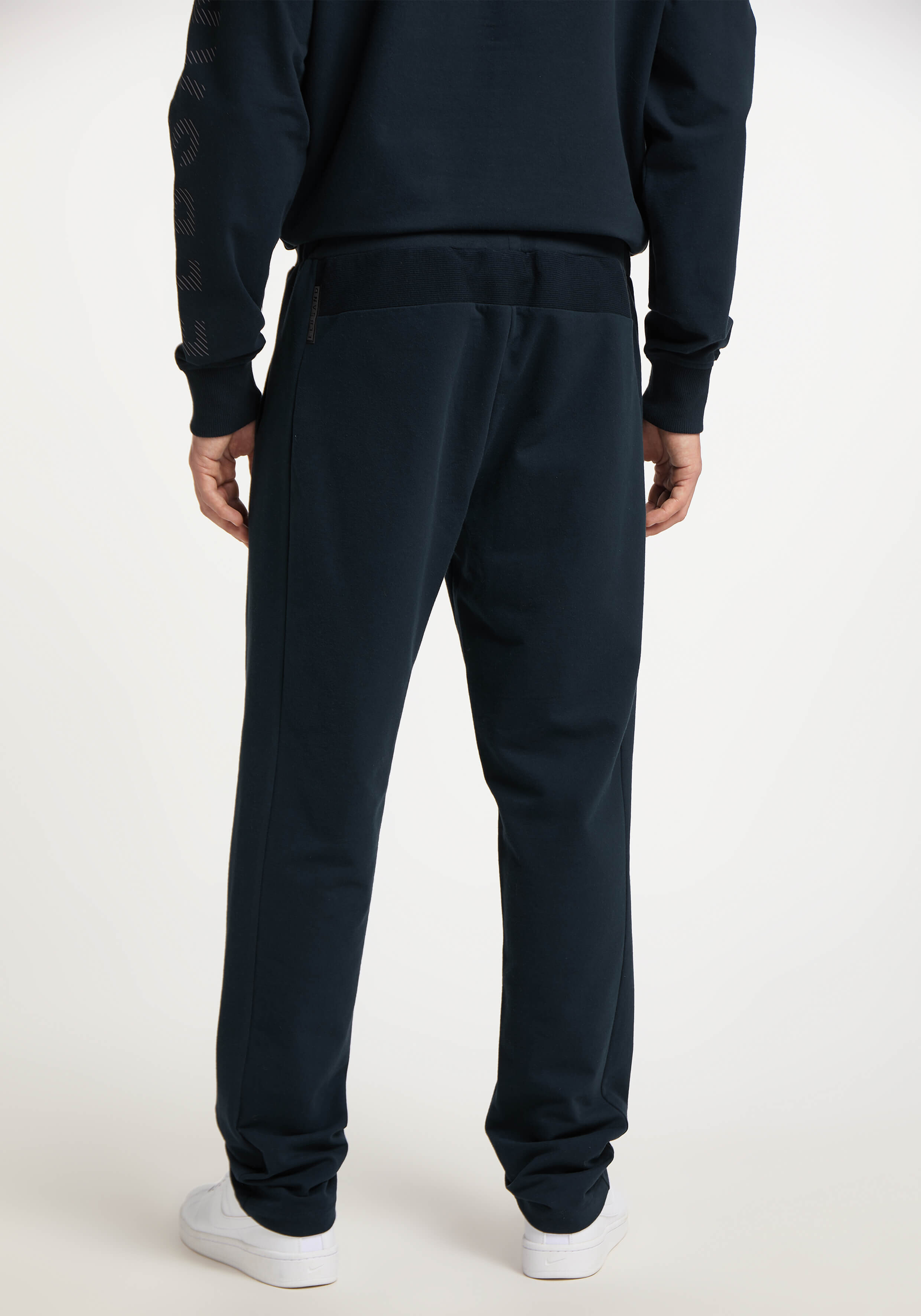 Rückansicht eines Mannes, der eine dunkelblaue Freizeit-Jogginghose und ein passendes Sweatshirt trägt.