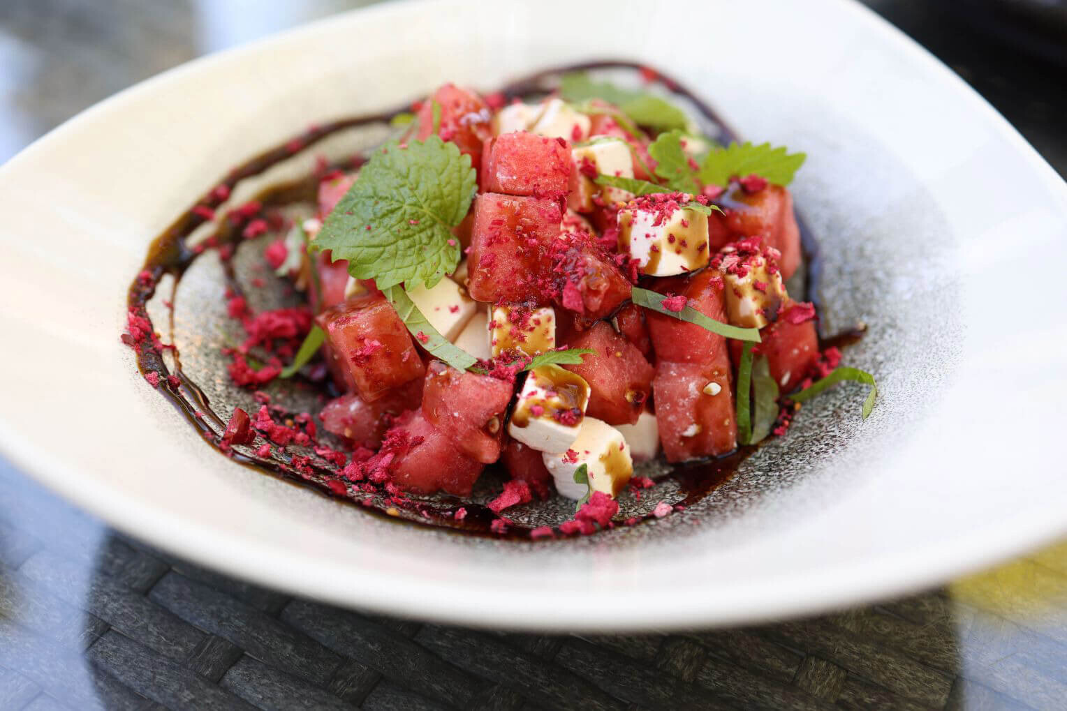 Bunter Wassermelonensalat mit Minze, Feta und Himbeerstaub in einer Schüssel.