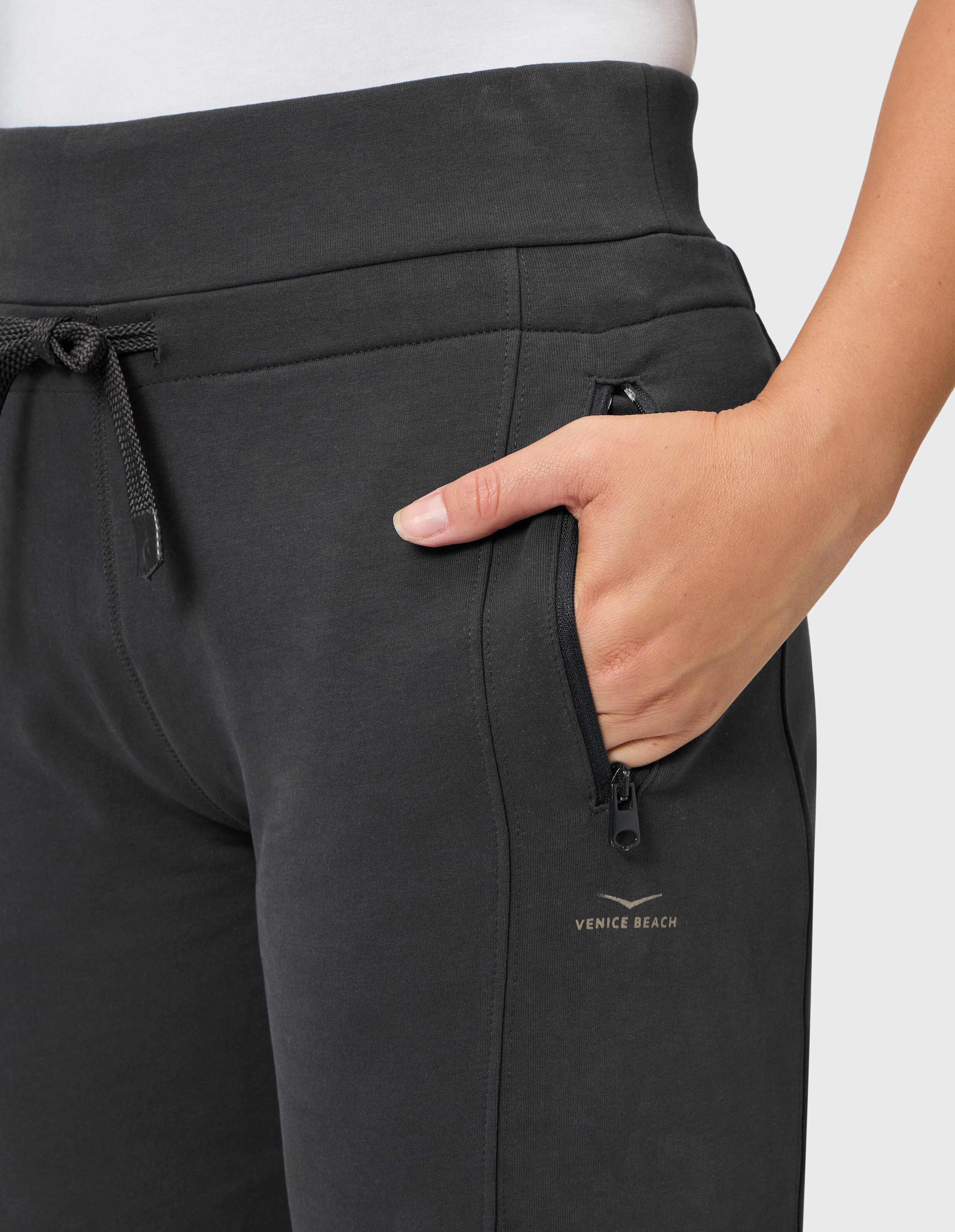 Nahaufnahme einer schwarzen, gemütlichen Lounge-Hose mit Kordelzug in der Taille und Reißverschlusstasche.