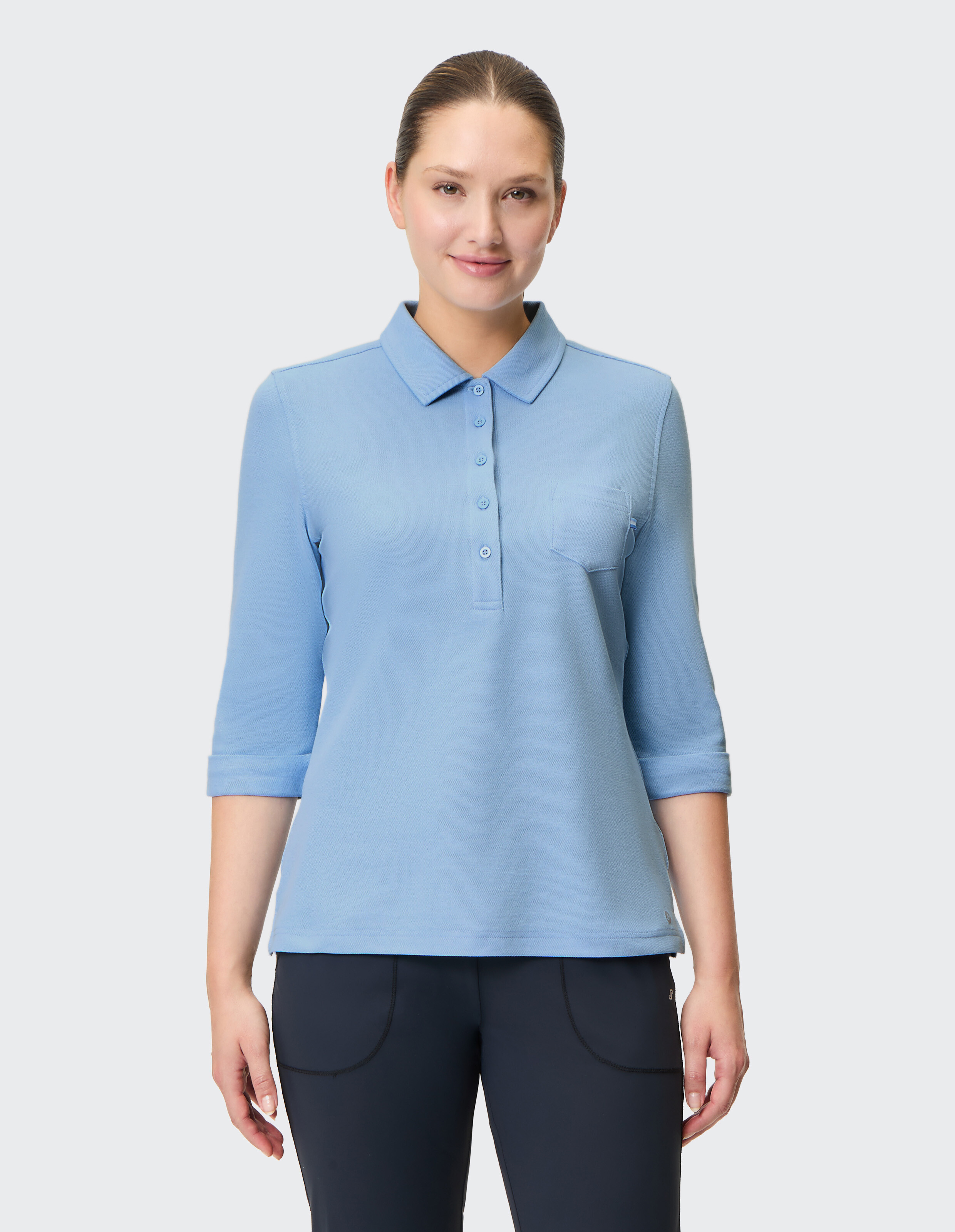 Frau trägt ein hellblaues Poloshirt mit Dreiviertelärmeln und einer Brusttasche.