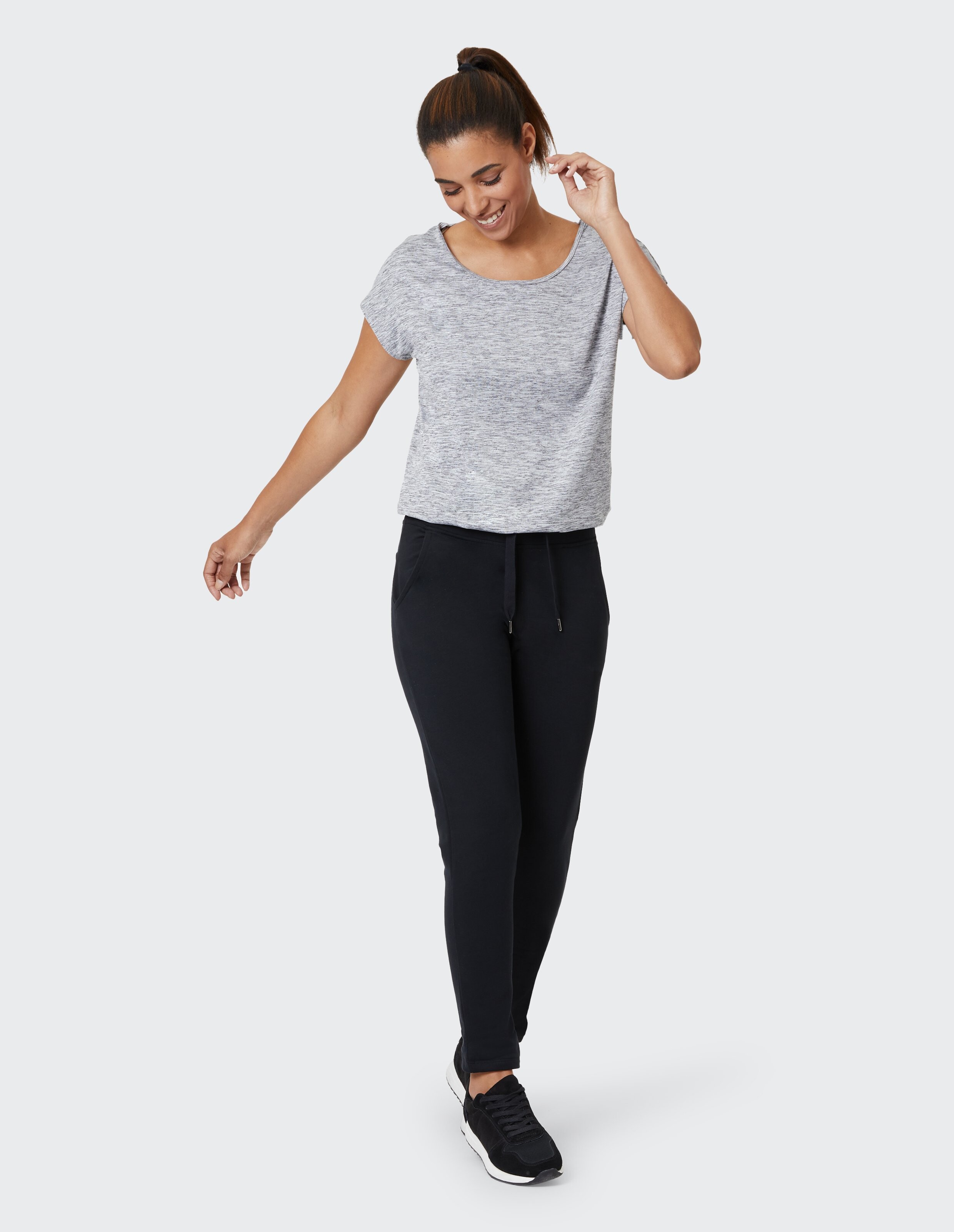 Frau trägt ein grau meliertes T-Shirt und schwarze Lounge-Jogginghosen für einen gemütlichen, lässigen Look.
