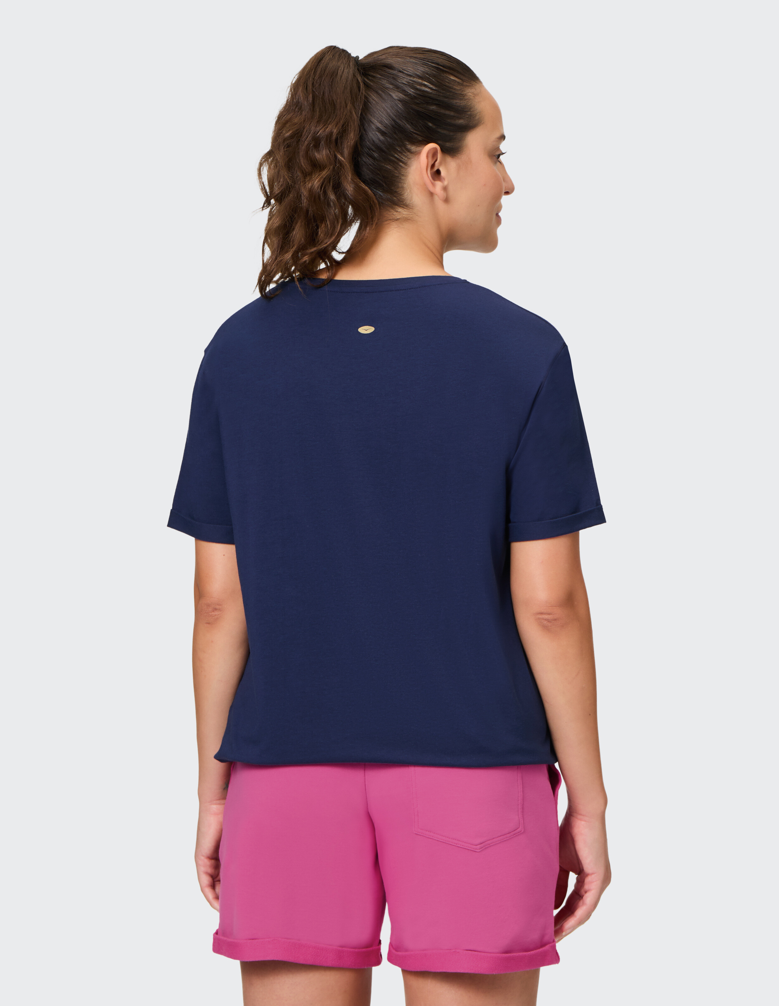 Frau trägt ein dunkelblaues Freizeit-T-Shirt und rosa Shorts für einen bequemen Lounge-Look.